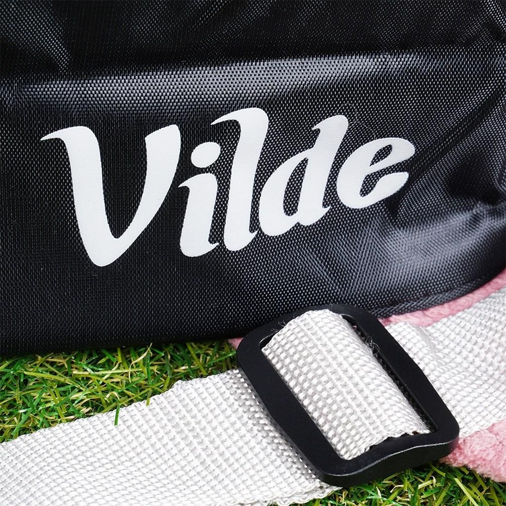Bolso negro con letras blancas "Vilde" y correa blanca con hebilla negra sobre césped.