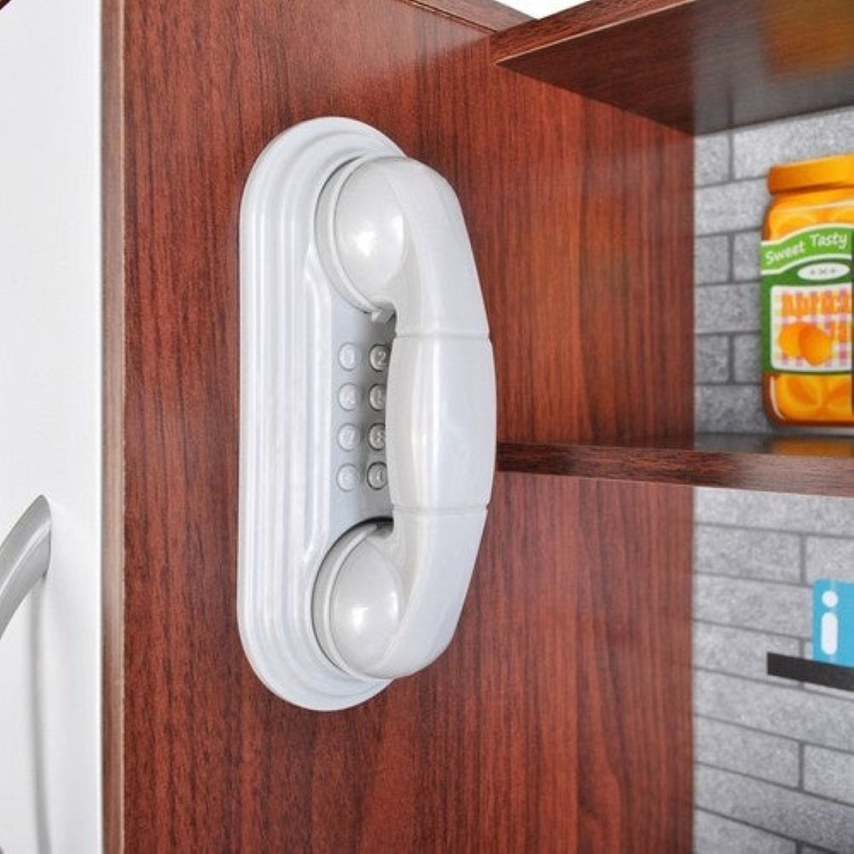 Un teléfono retro blanco con botones está montado en una superficie de madera. Al lado, una repisa con mermelada.