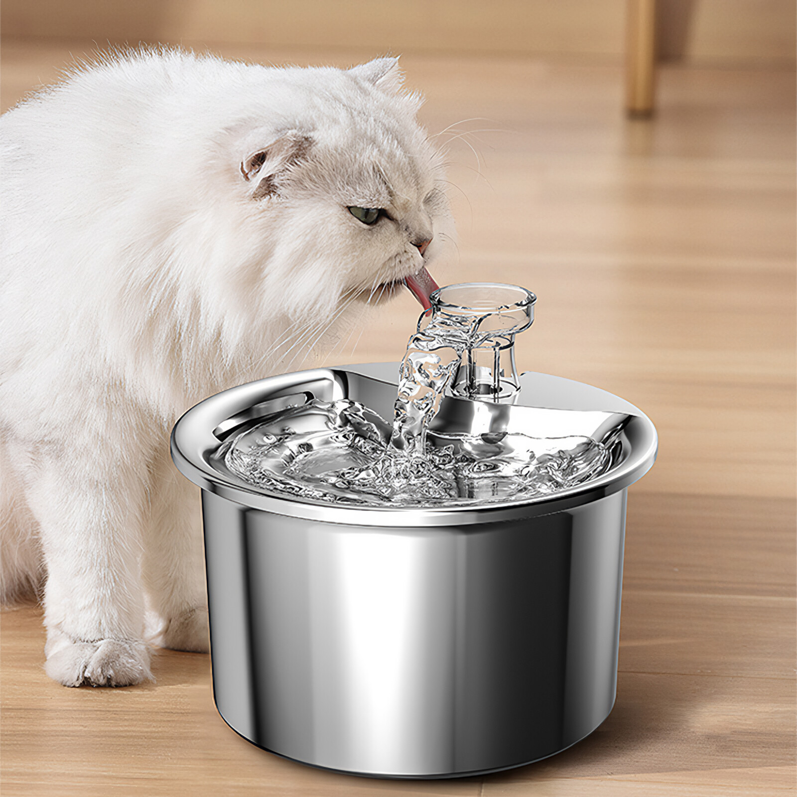 Eine weiße Katze trinkt aus einem silbernen Trinkbrunnen.