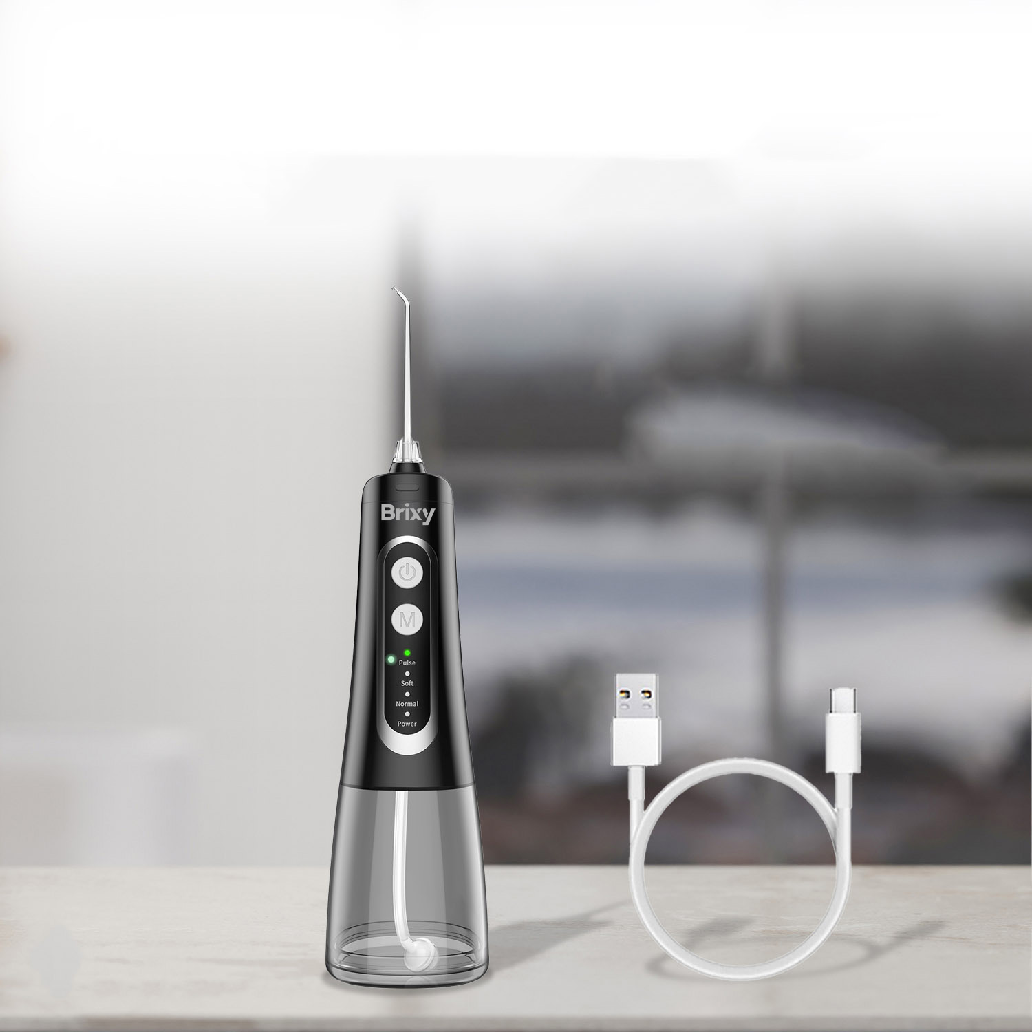 Zwarte waterflosser met USB-oplaadkabel op een tafel.
