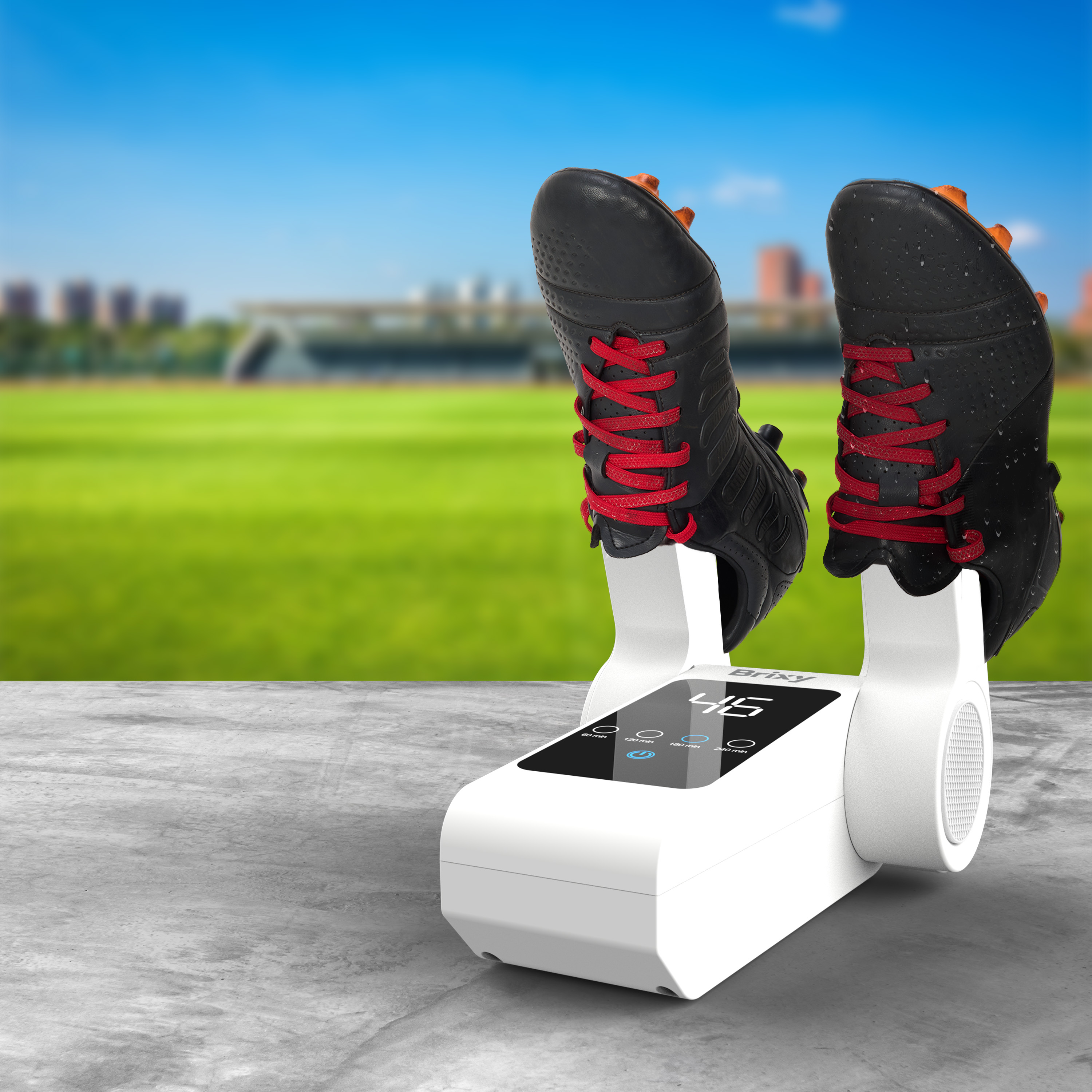 A white shoe dryer holding black soccer cleats with red laces, outdoors.