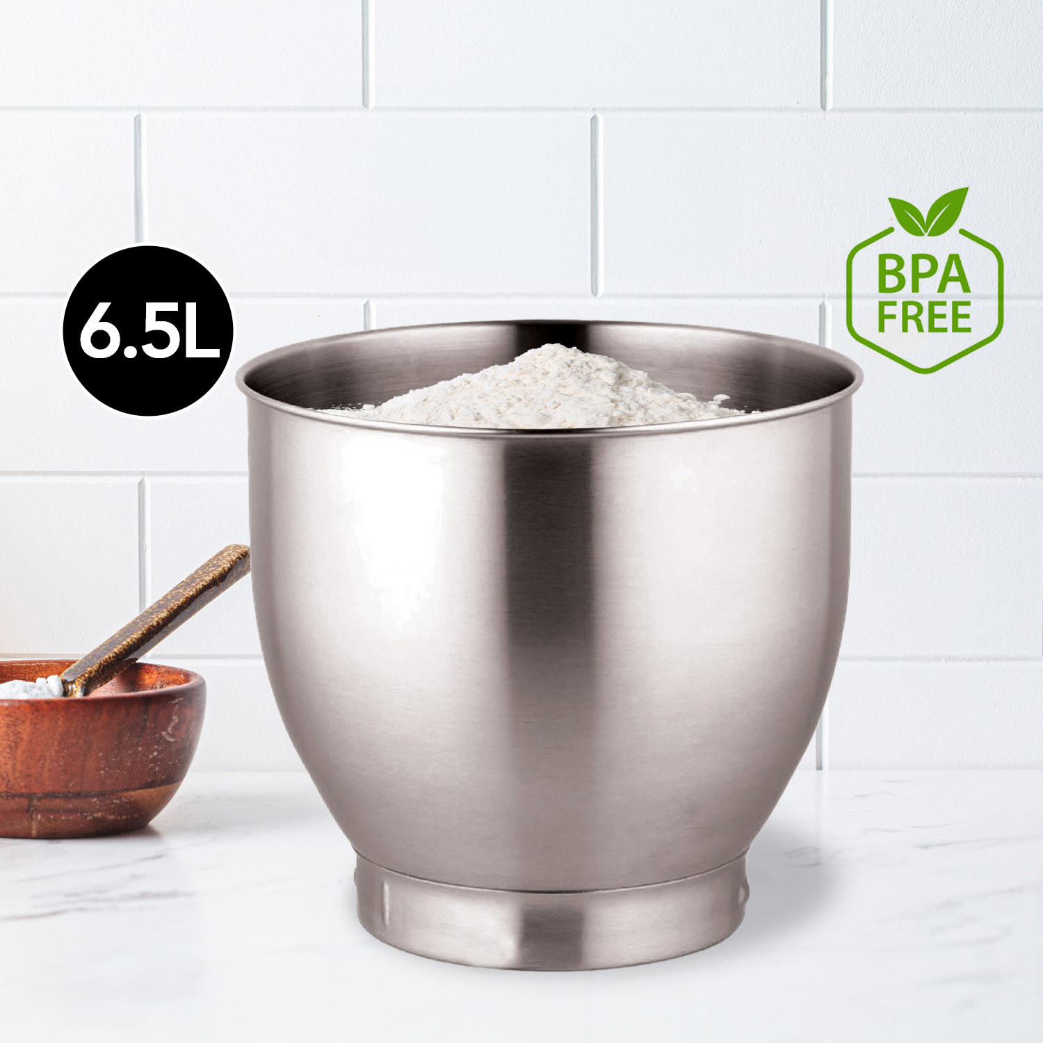 Stainless steel bowl filled with flour, next to it a wooden bowl with a spoon.