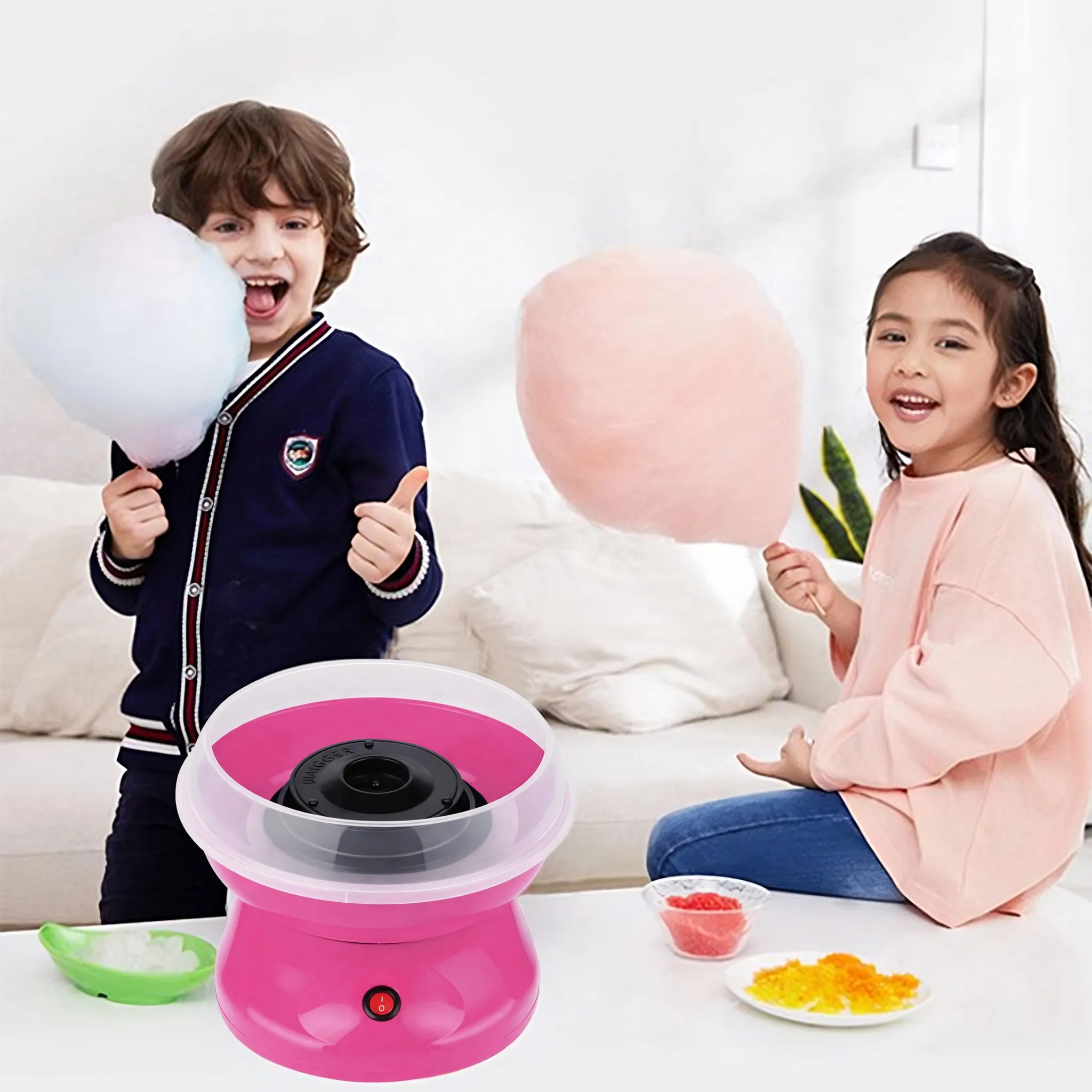 Zwei Kinder halten Zuckerwatte. Ein rosa Zuckerwattemaschine steht auf dem Tisch.