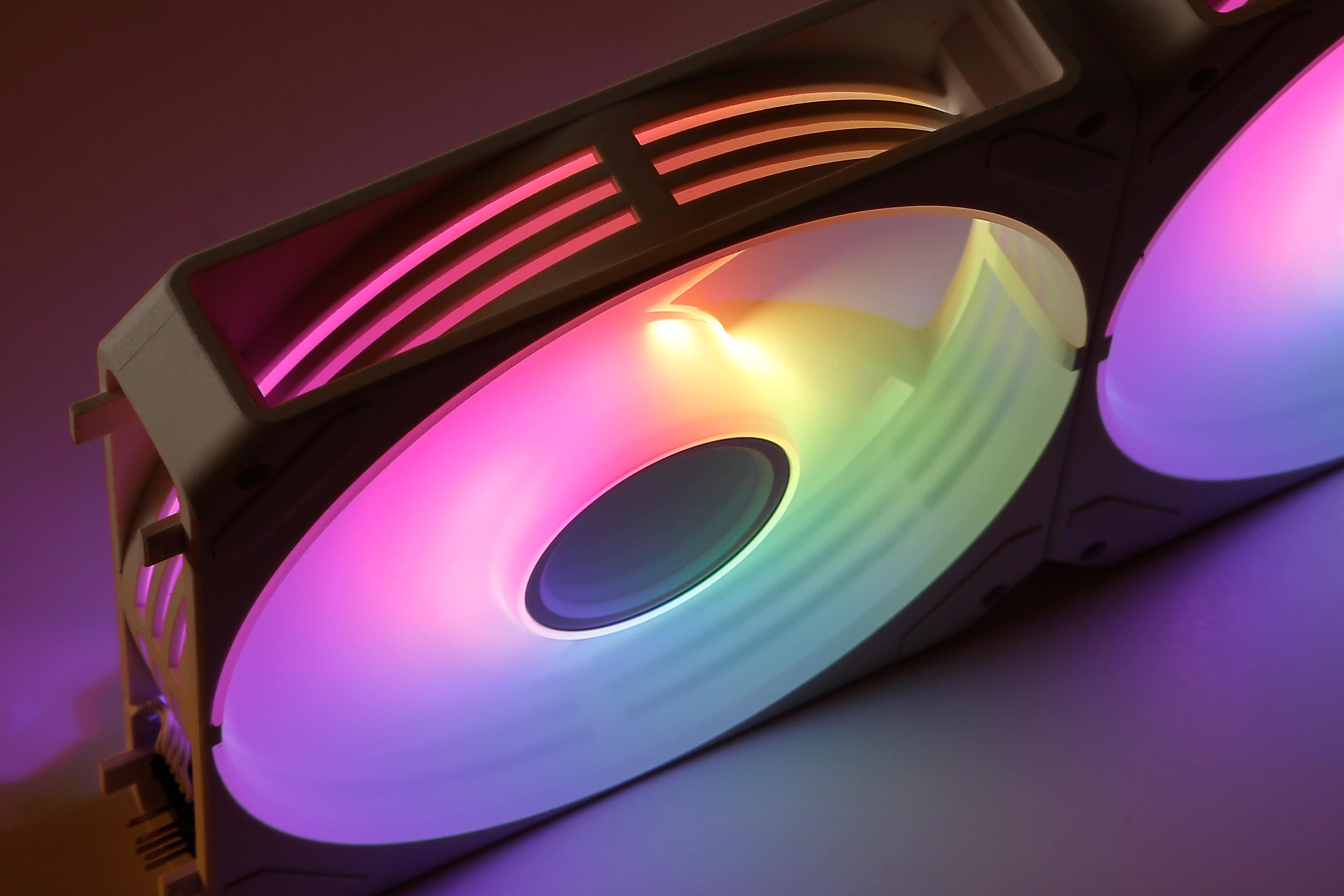 Un ventilador de PC con coloridos LEDs RGB brilla en tonos rosa, amarillo y verde.