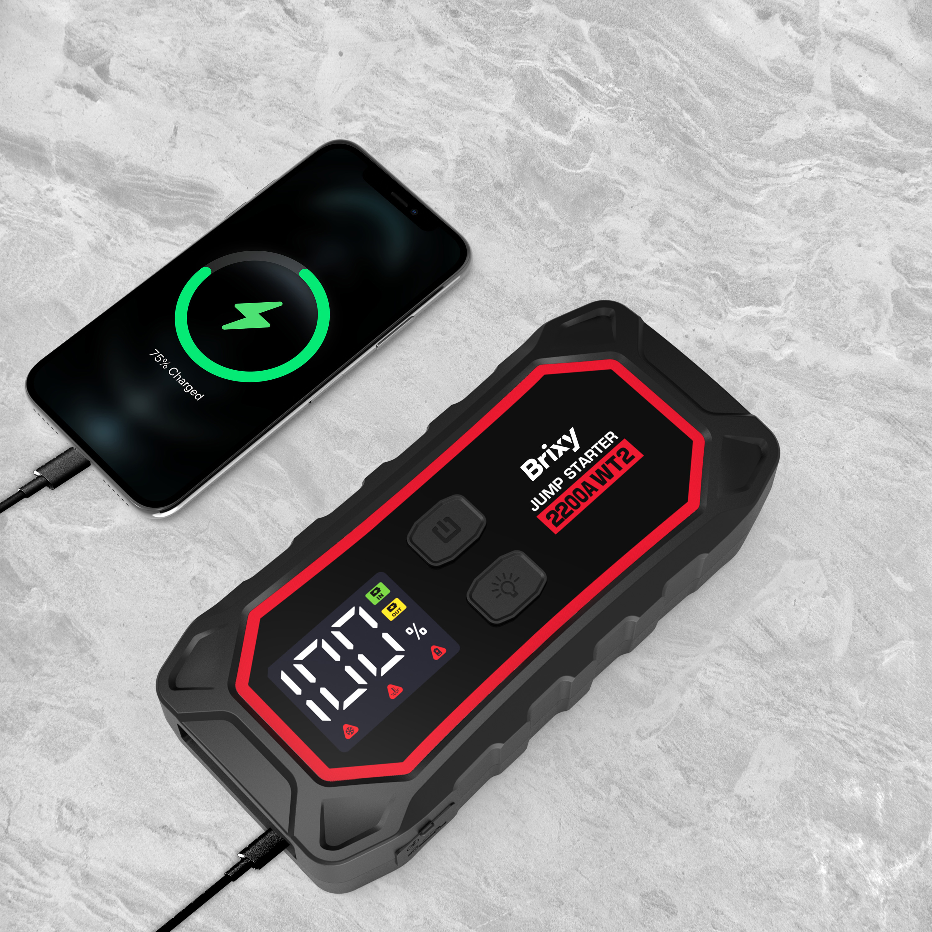 Een zwarte Briy startbooster oplader met rode accenten naast een iPhone die 75% is opgeladen.