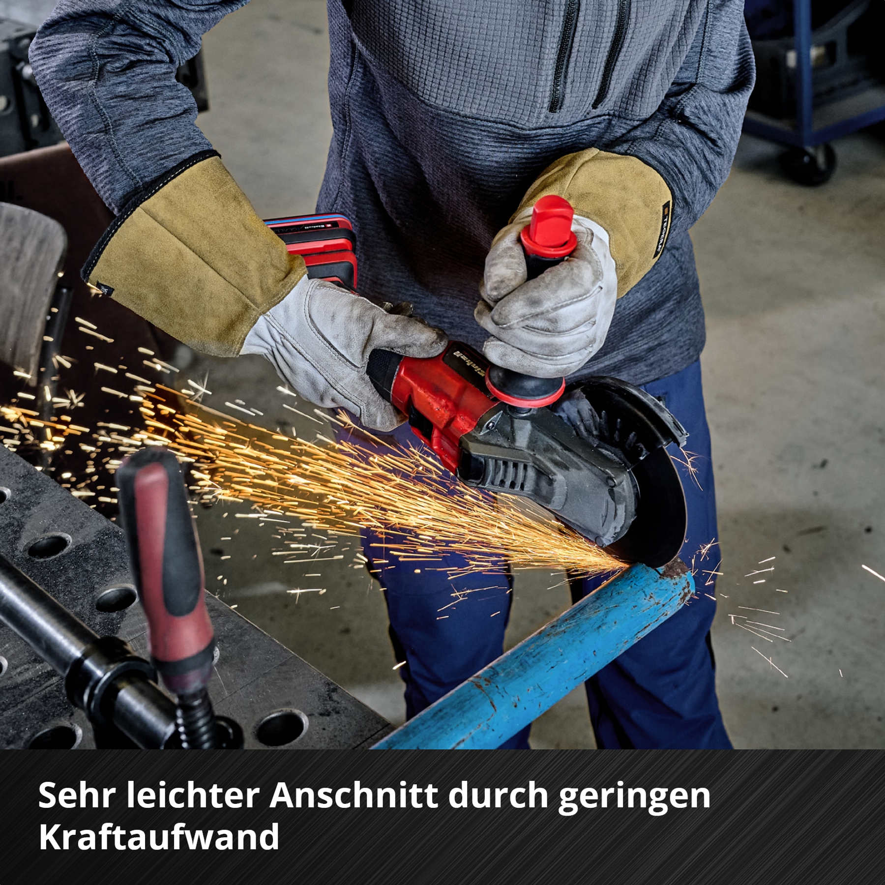 Ein Mann mit Schutzhandschuhen schneidet mit einem Winkelschleifer ein Rohr.