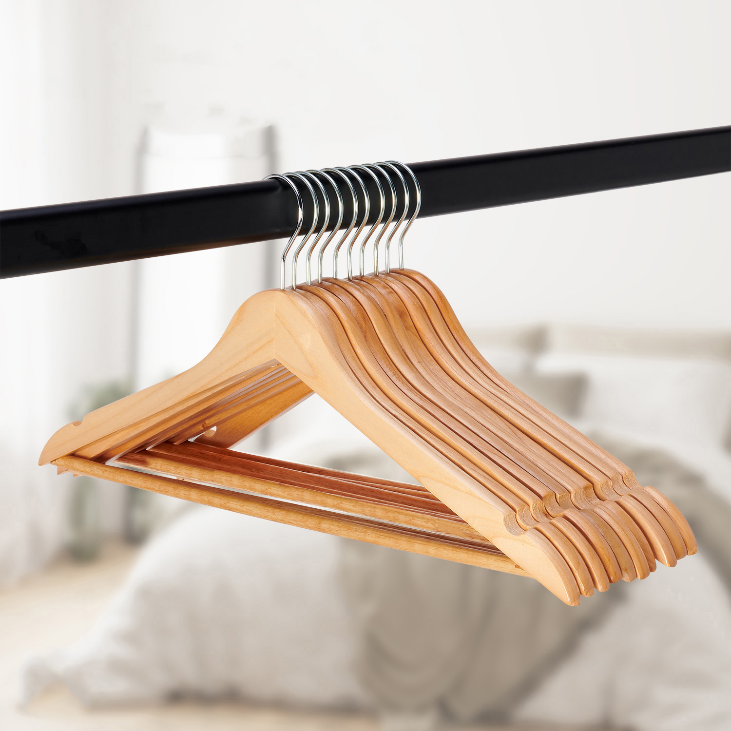 Houten kledinghangers aan een zwarte staaf, wazige achtergrond met bed.