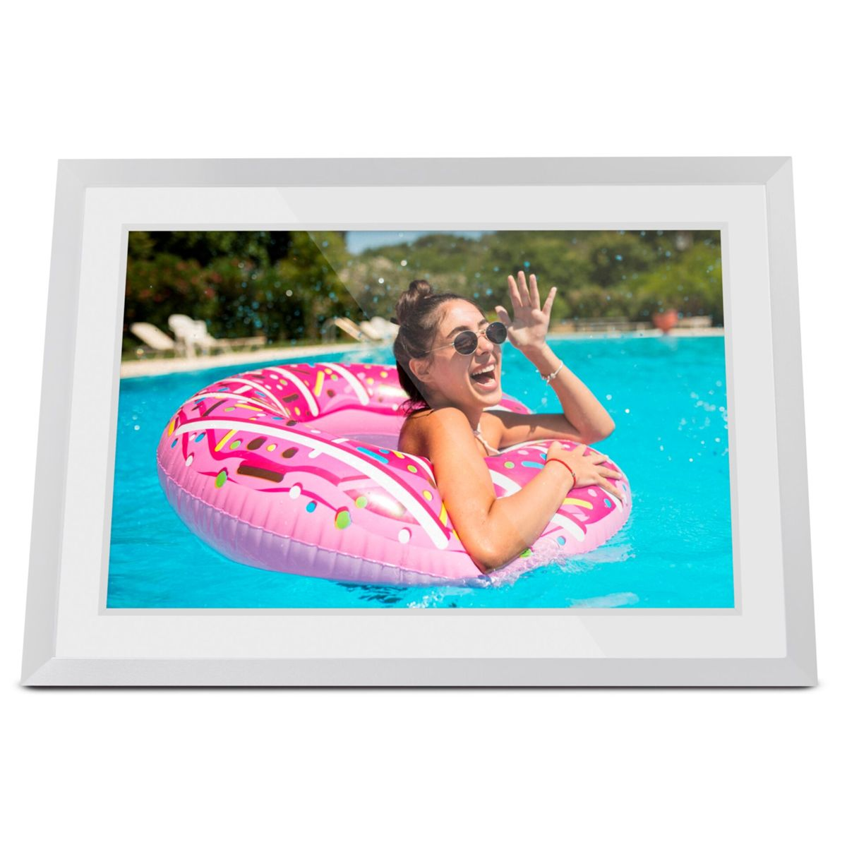 Femme souriante dans un bouée donut rose fait un signe dans une piscine.