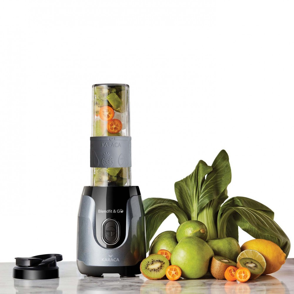 Yanında meyve ve sebzeler bulunan bir blender.