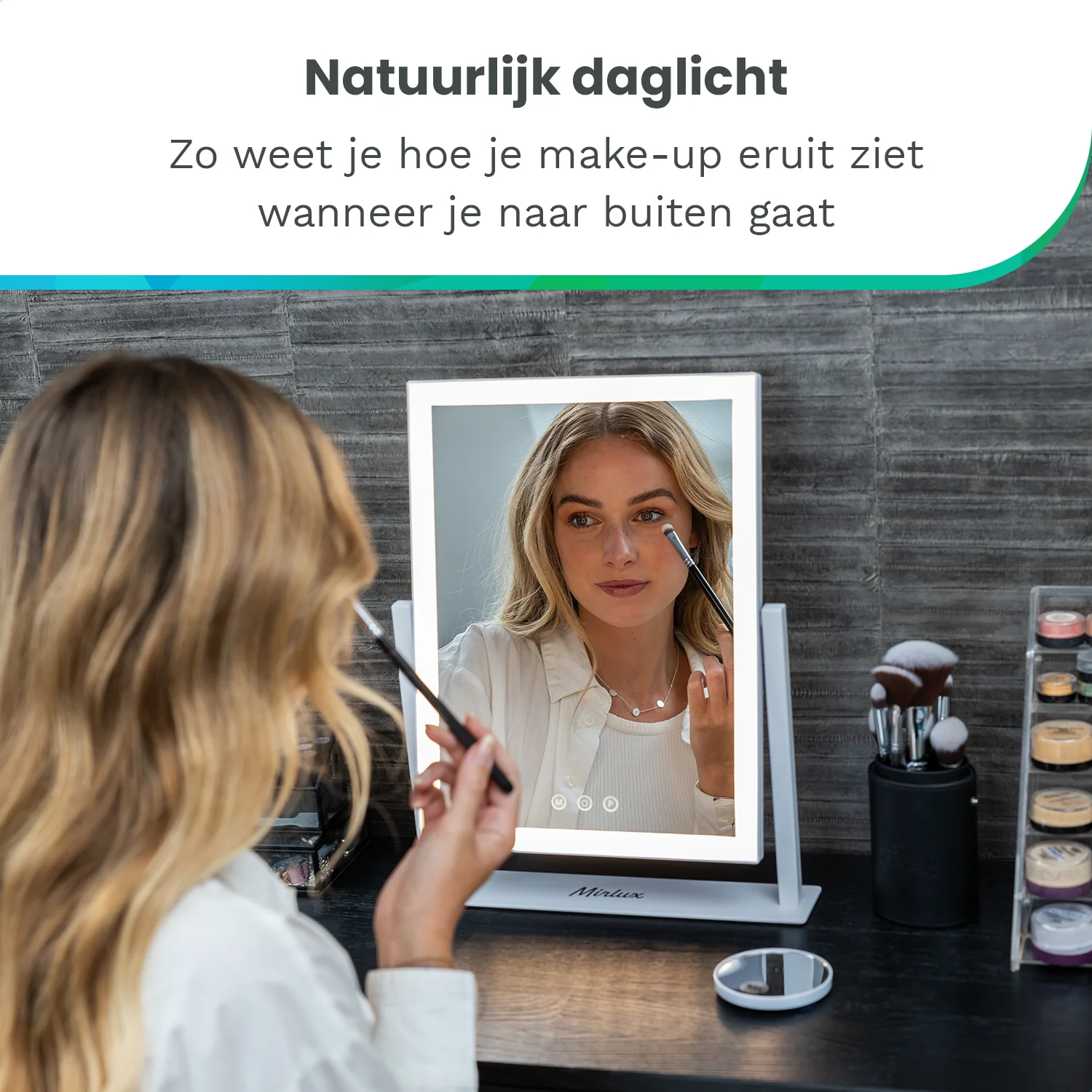 A woman with blonde hair applies makeup in front of a lighted mirror.