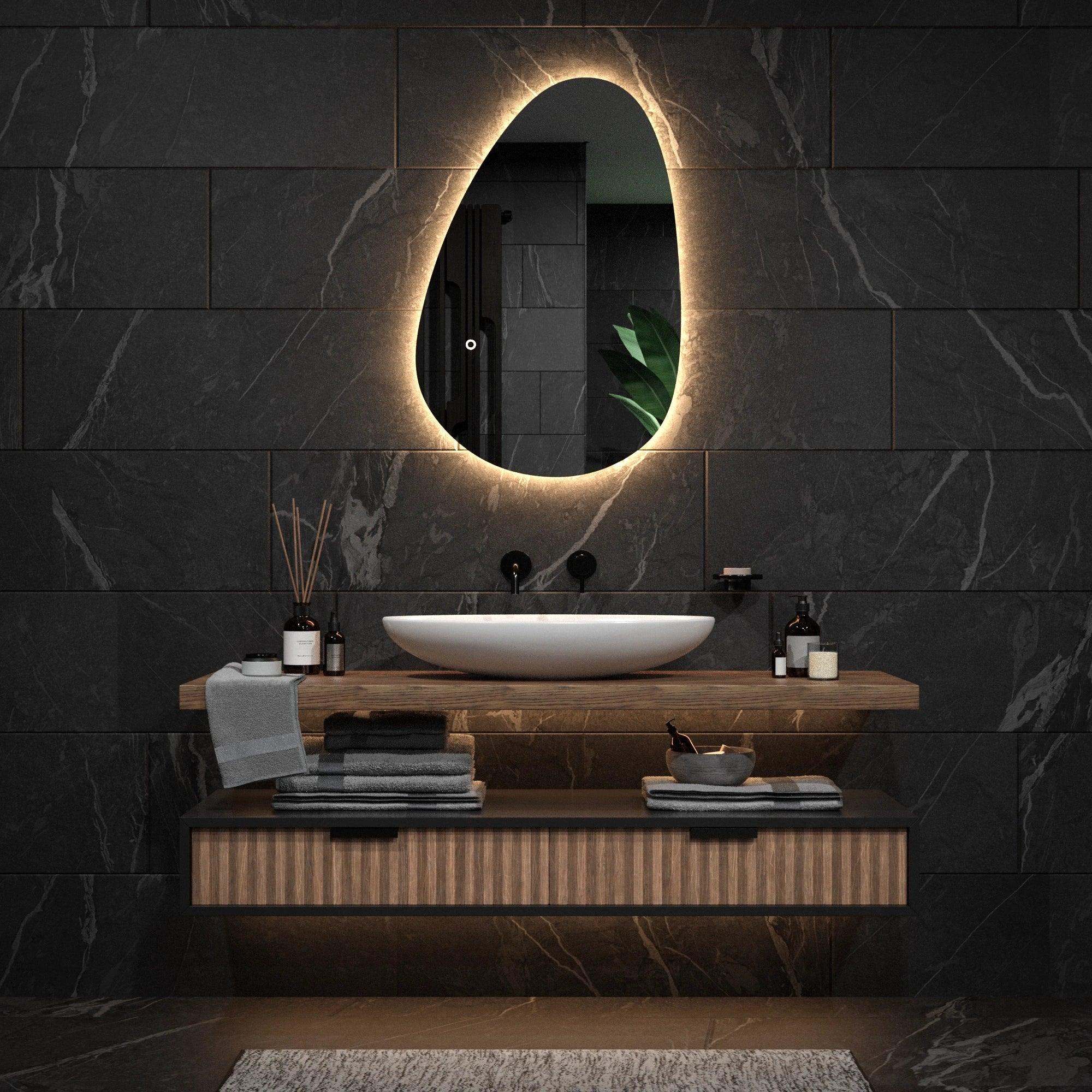 Een moderne badkamer met een ovale spiegel, wastafel en donkere tegelmuren.
