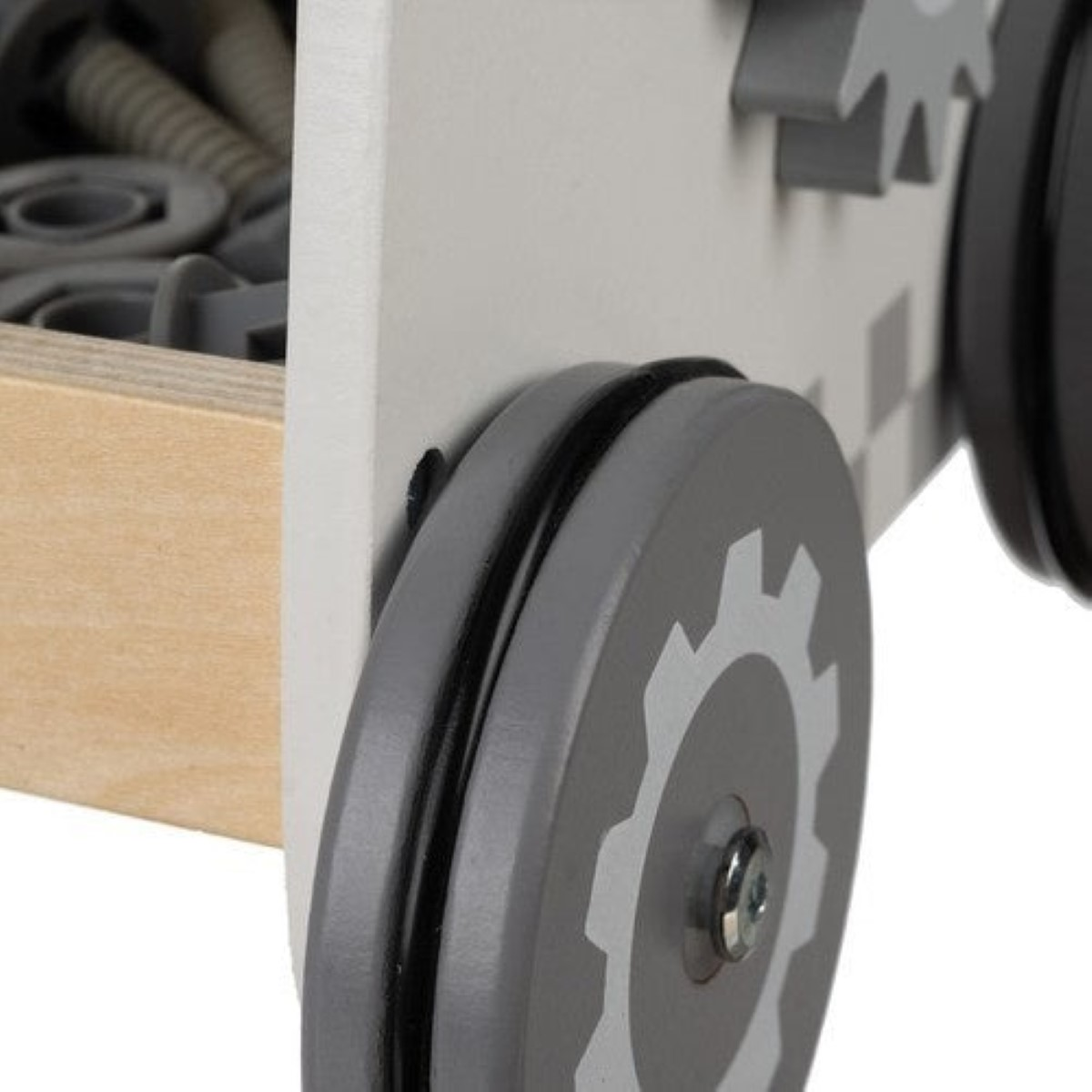 Rueda de juguete gris con patrón de engranaje en caja de madera con tornillos.