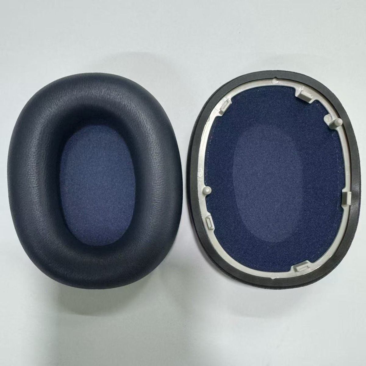 Due cuscinetti per cuffie blu navy, uno in ecopelle, l'altro con cornice.