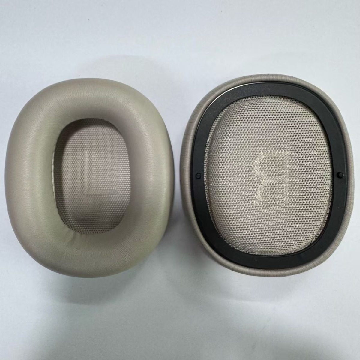 Due cuscinetti auricolari beige per cuffie, uno in tessuto, l'altro in ecopelle.