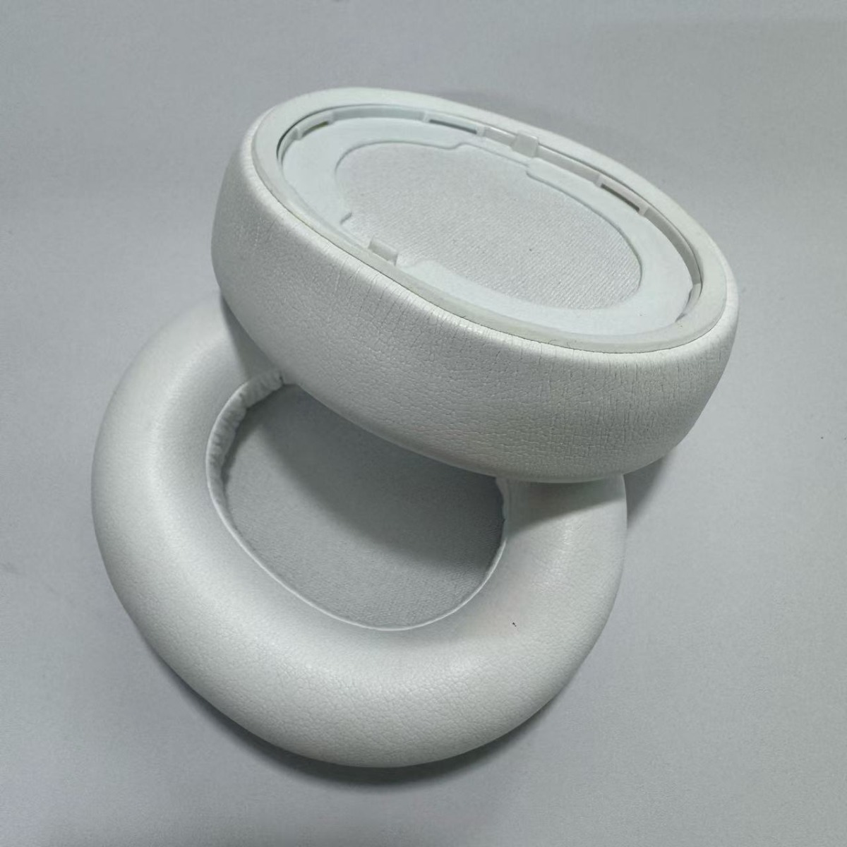 Due cuscinetti auricolari bianchi per cuffie giacciono uno accanto all'altro.