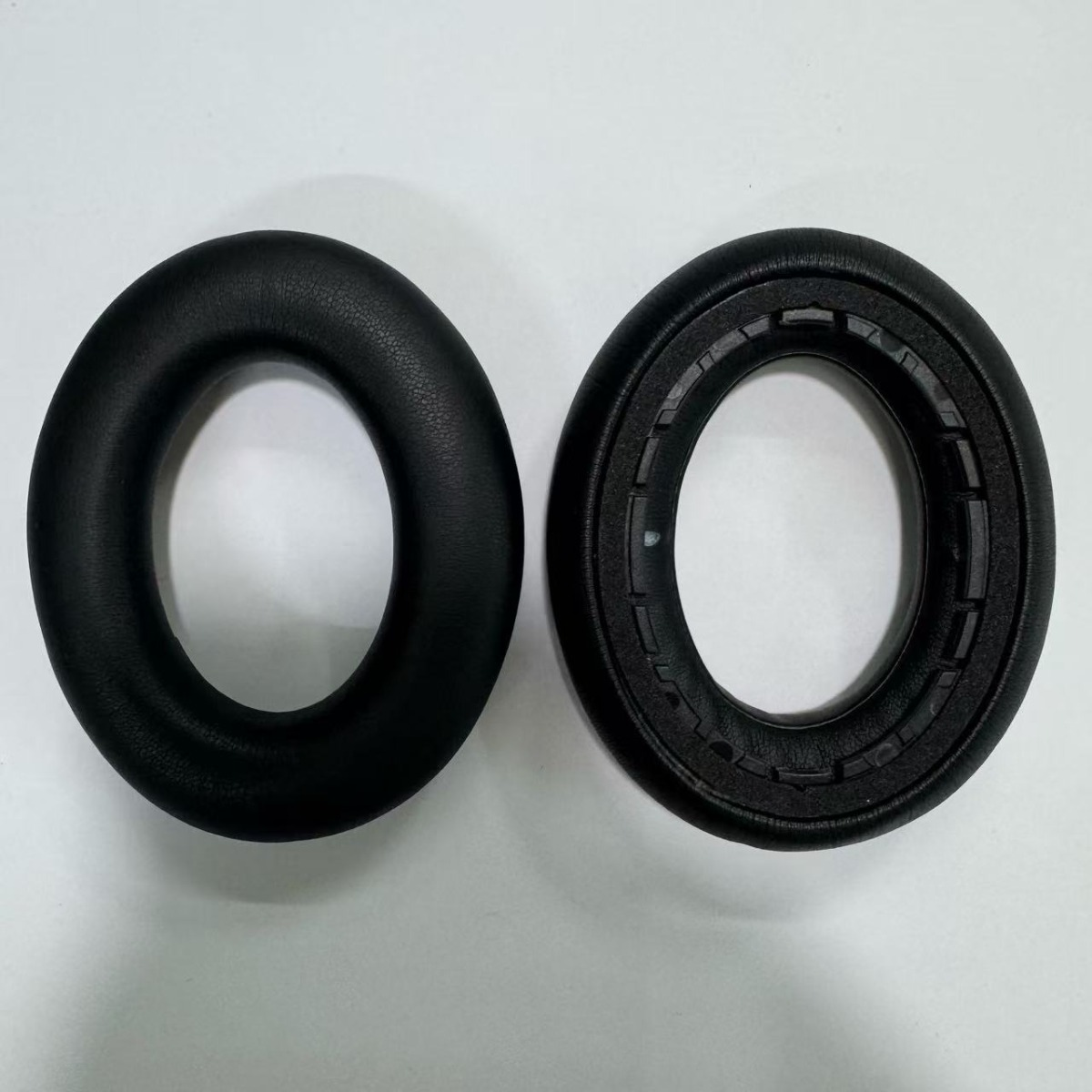 Two black headphone ear pads side by side on a white background.