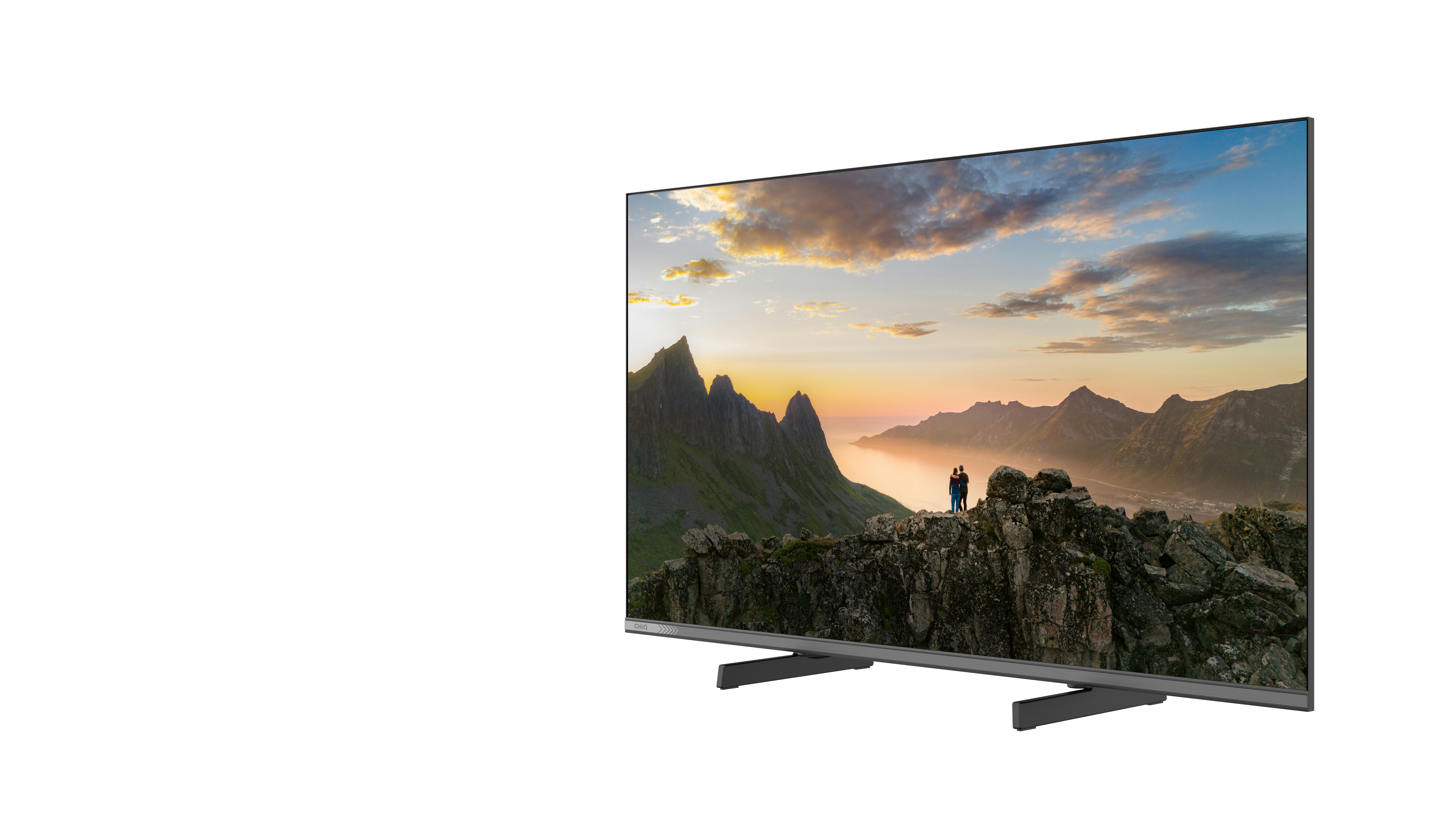 Para stoi na skałach, patrząc na górzysty krajobraz o zachodzie słońca.