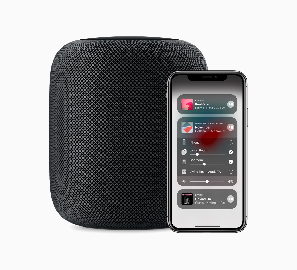 Ein schwarzer HomePod-Lautsprecher steht neben einem iPhone, das die Home-App anzeigt.