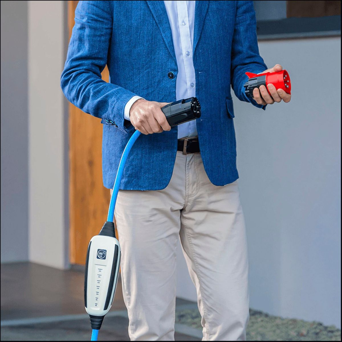 Mężczyzna w niebieskiej marynarce trzyma kabel ładujący i wtyczkę.