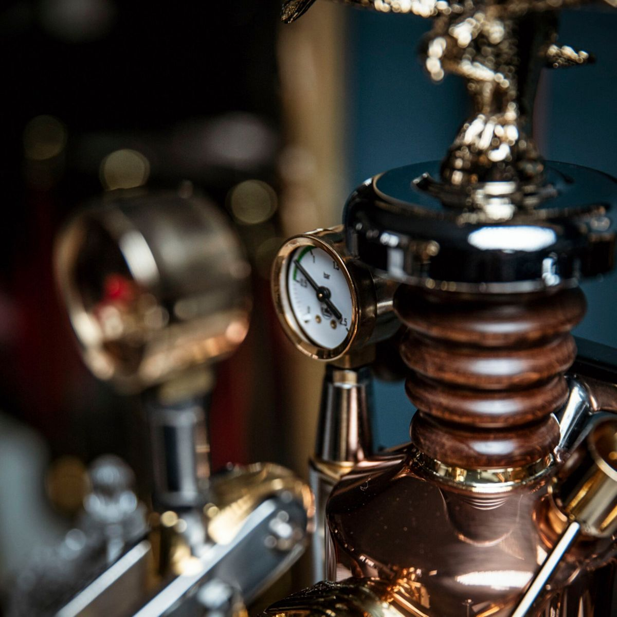 Miernik z białą tarczą i igłą obok mechanizmu miedzianego, drewnianego i złotego.