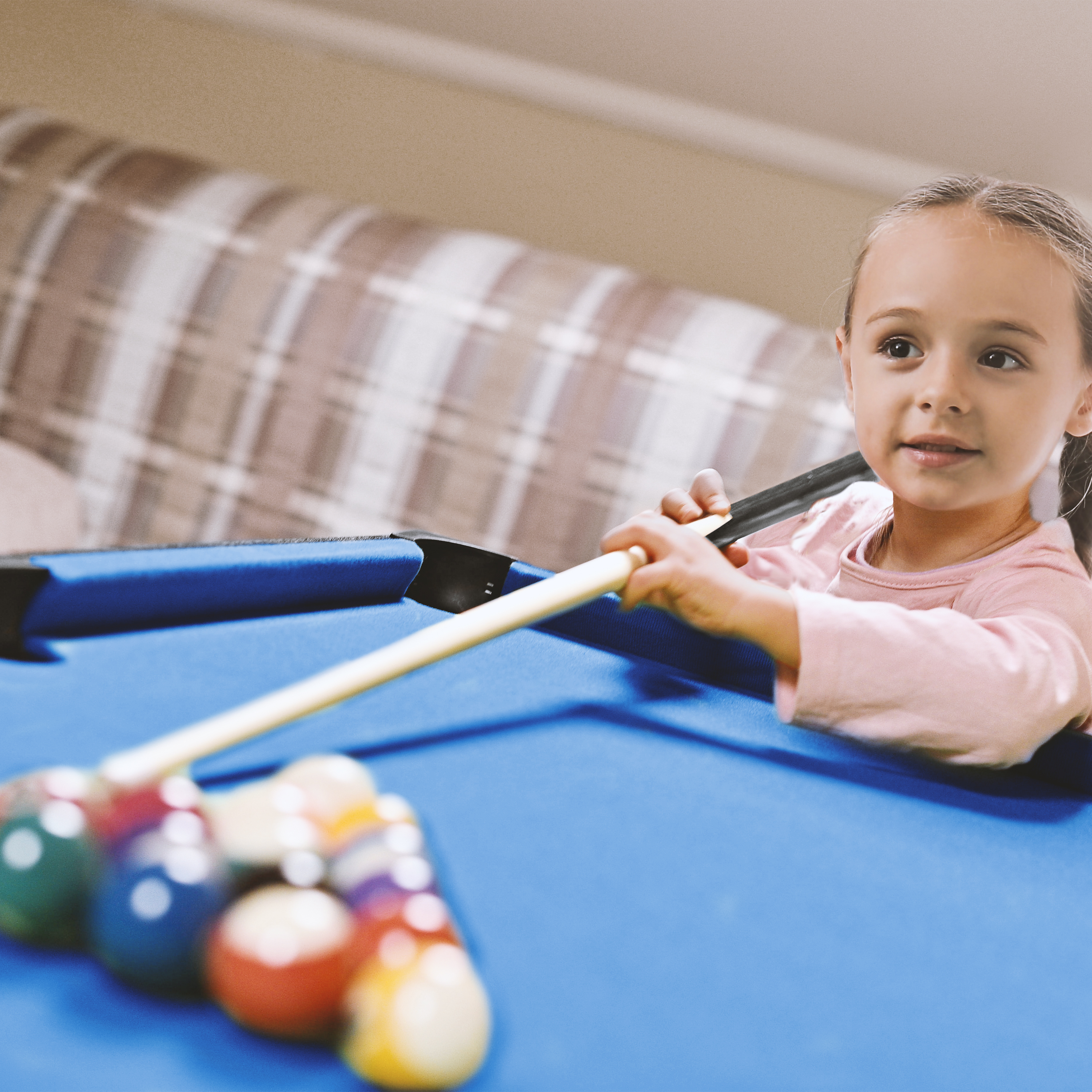 Ein junges Mädchen spielt Billard auf einem blauen Tisch.