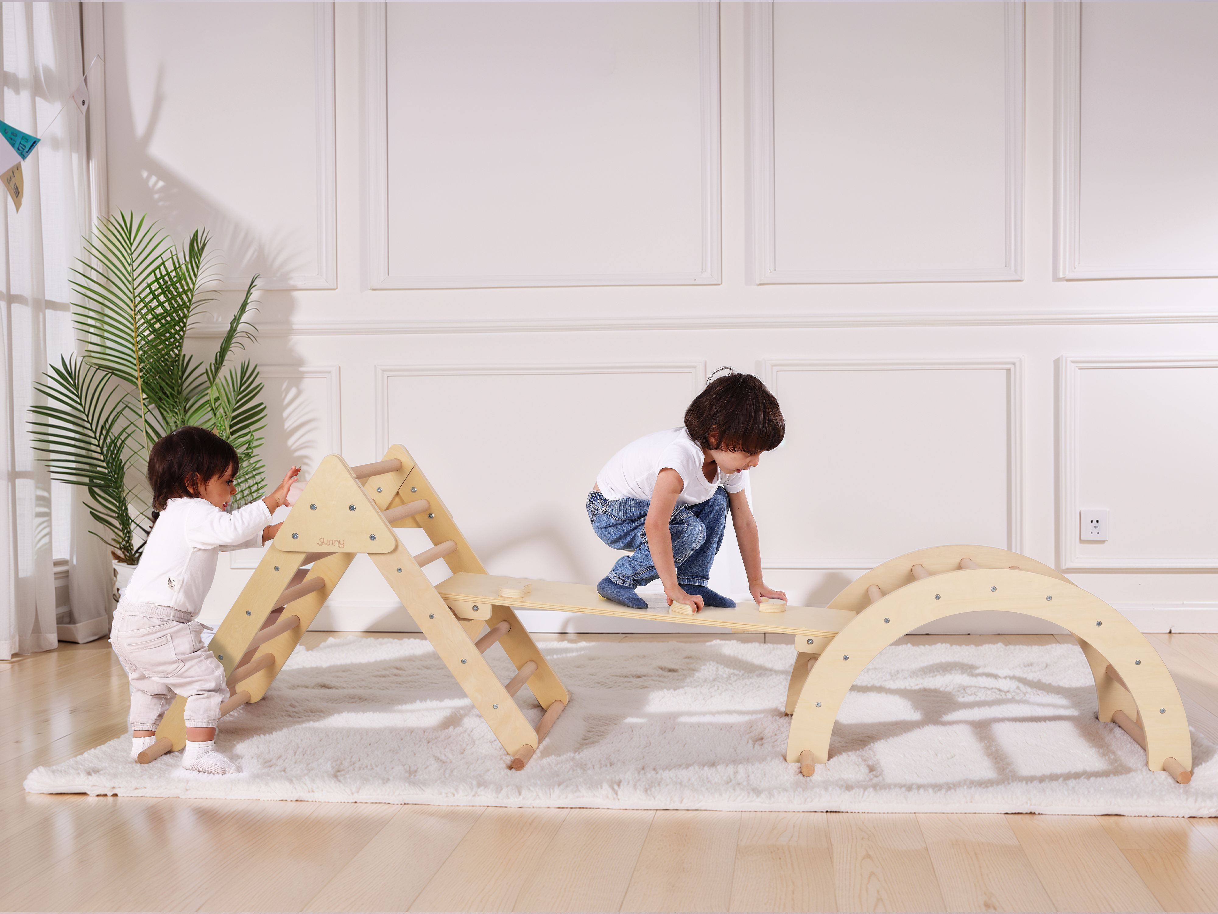 Zwei Kinder spielen auf Holzspielgeräten in einem hellen Raum.