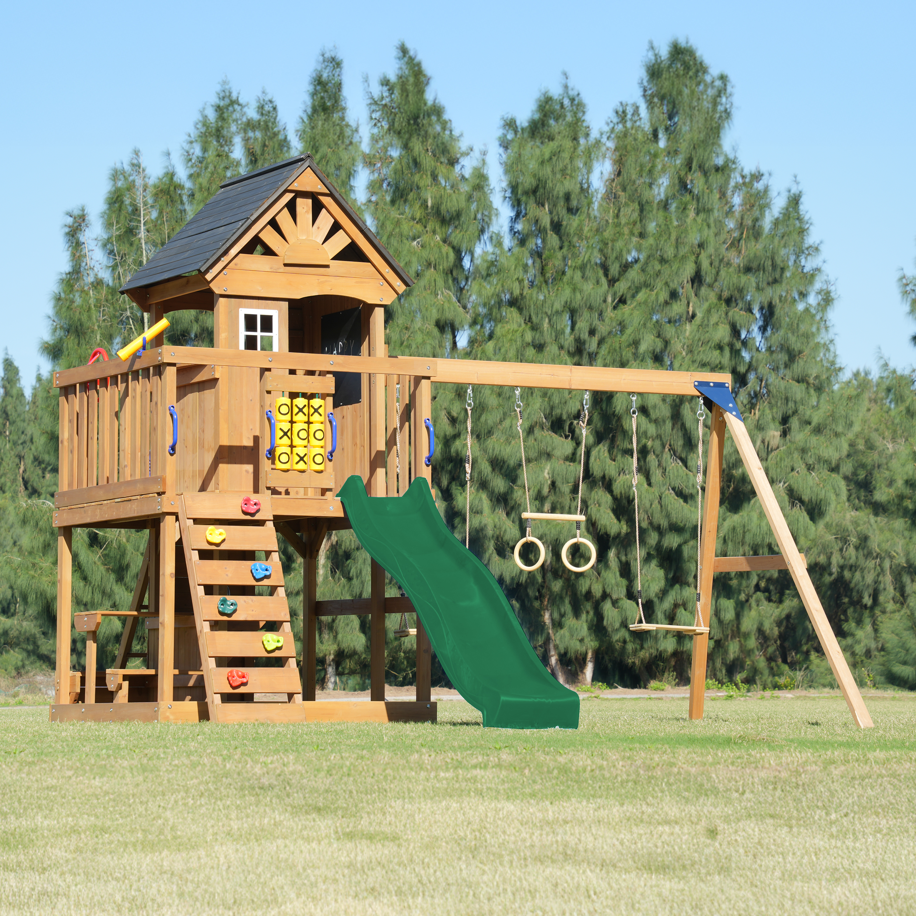 Ein hölzerner Spielturm mit Rutsche, Schaukeln und Kletterwand auf Gras.