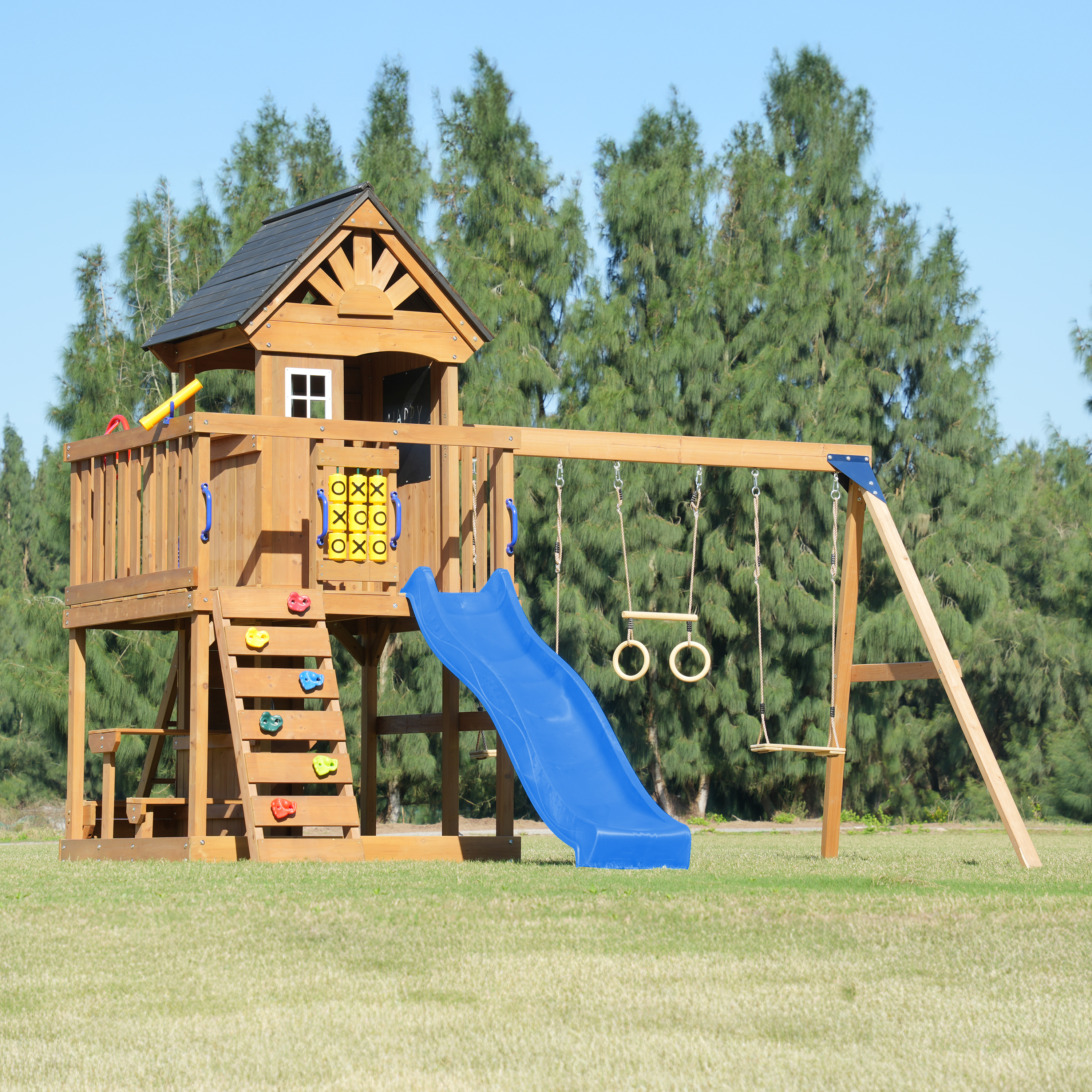 Ein hölzerner Spielturm mit Rutsche, Schaukeln und Kletterwand im Freien.