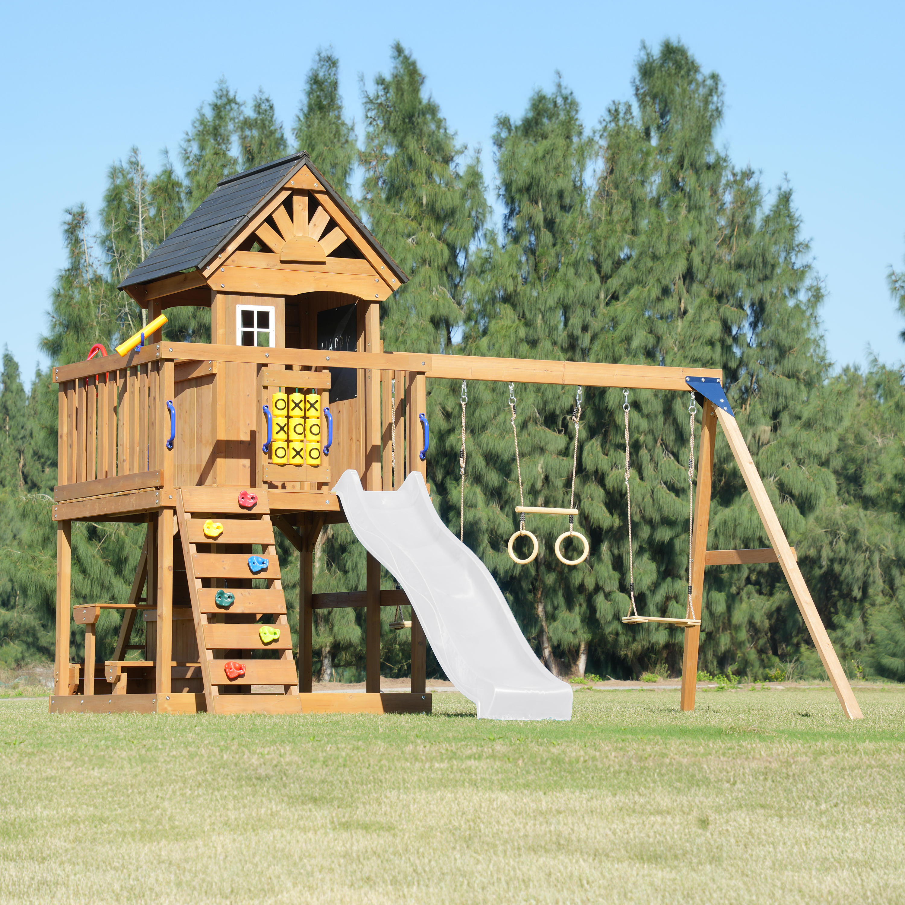 Ein hölzerner Spielturm mit Rutsche, Schaukeln und Kletterwand.