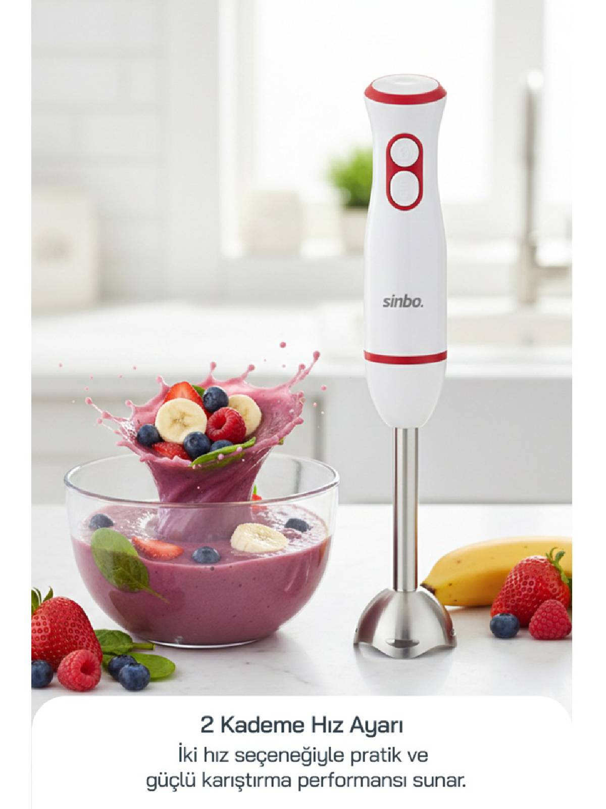 Kırmızı detaylı beyaz el blenderı, meyveli smoothie ve meyveler olan kase yanında.