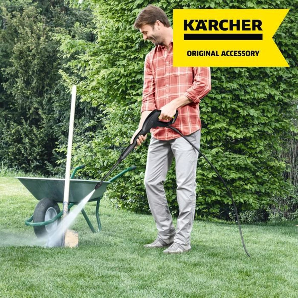 Man pressure washes a wheelbarrow on a lawn.
