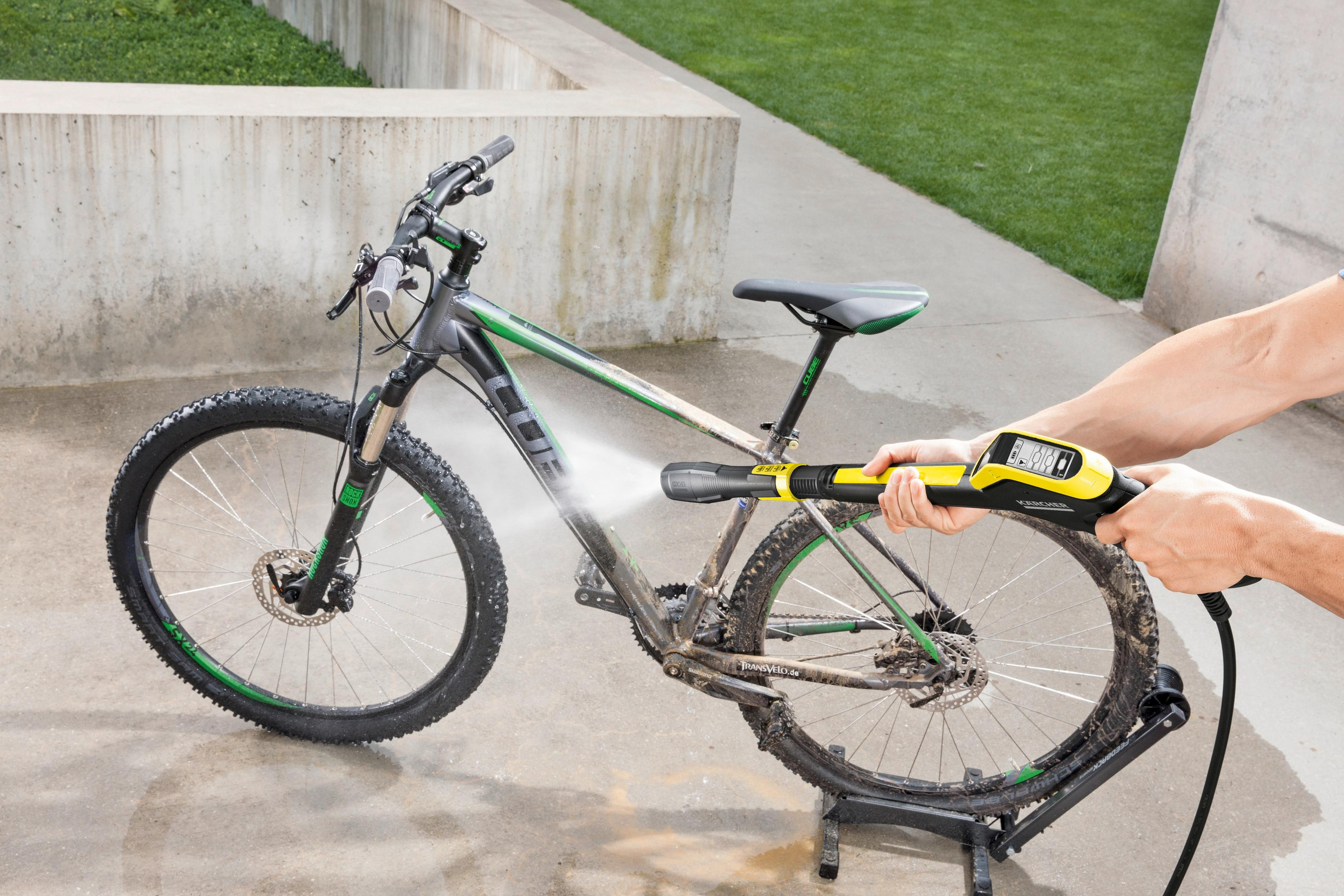 Persona che pulisce una mountain bike sporca con idropulitrice.