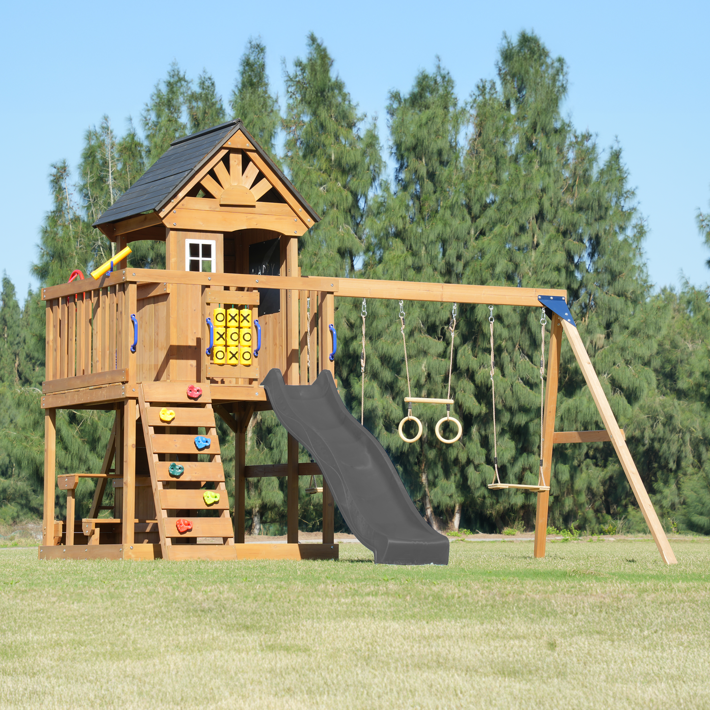 Ein hölzerner Spielturm mit Rutsche, Schaukeln und Kletterwand.