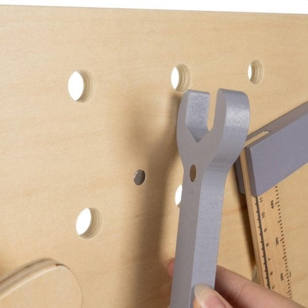 Banco de trabajo de madera con llave inglesa y regla. Mano sujetando llave.