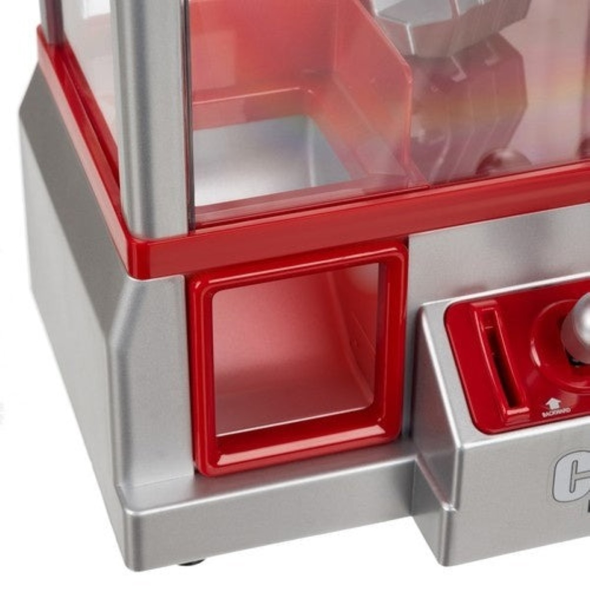 Primer plano de una máquina de garra de juguete con cuerpo plateado y detalles rojos.
