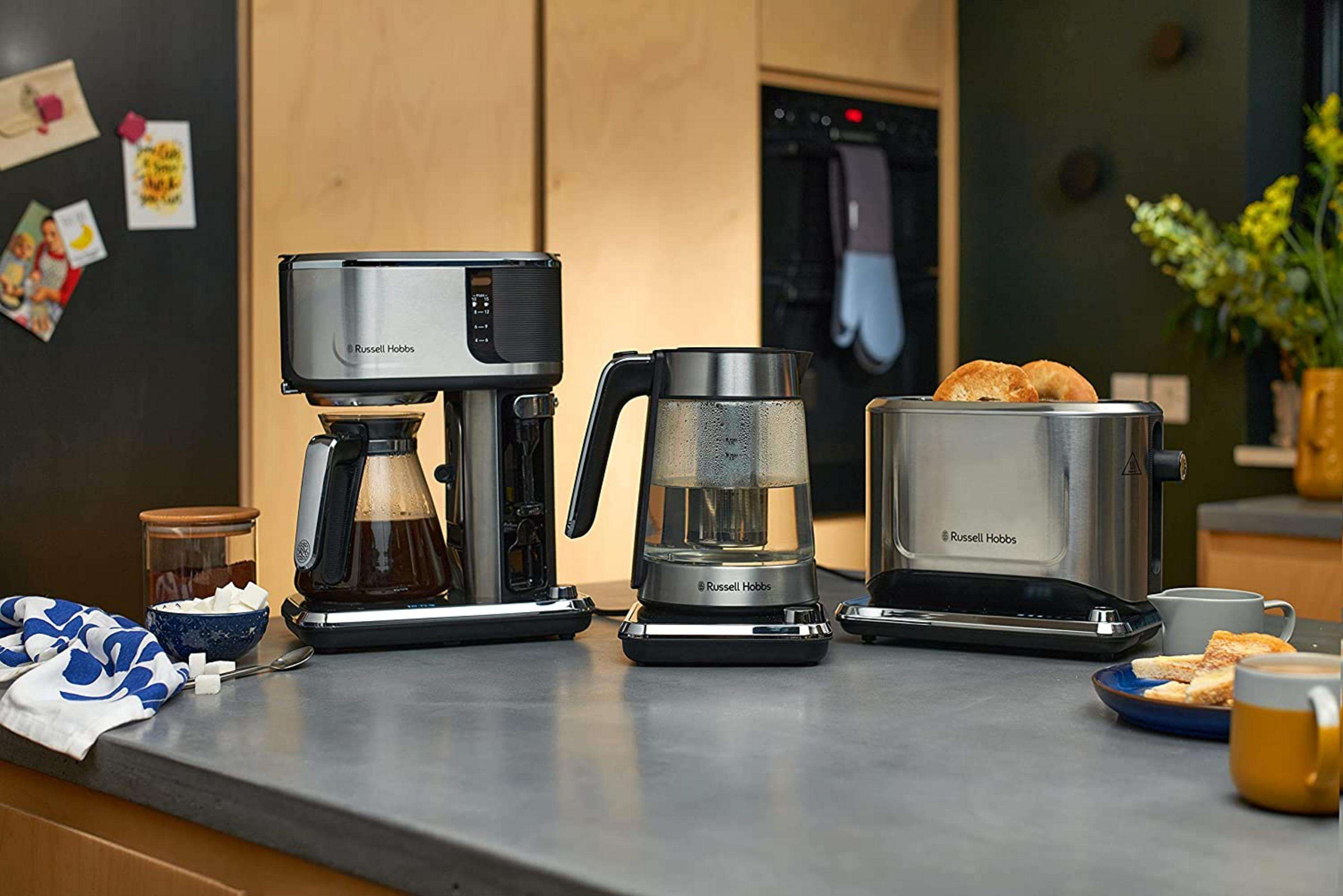 Cafetière, bouilloire et grille-pain en acier inoxydable sur un comptoir.