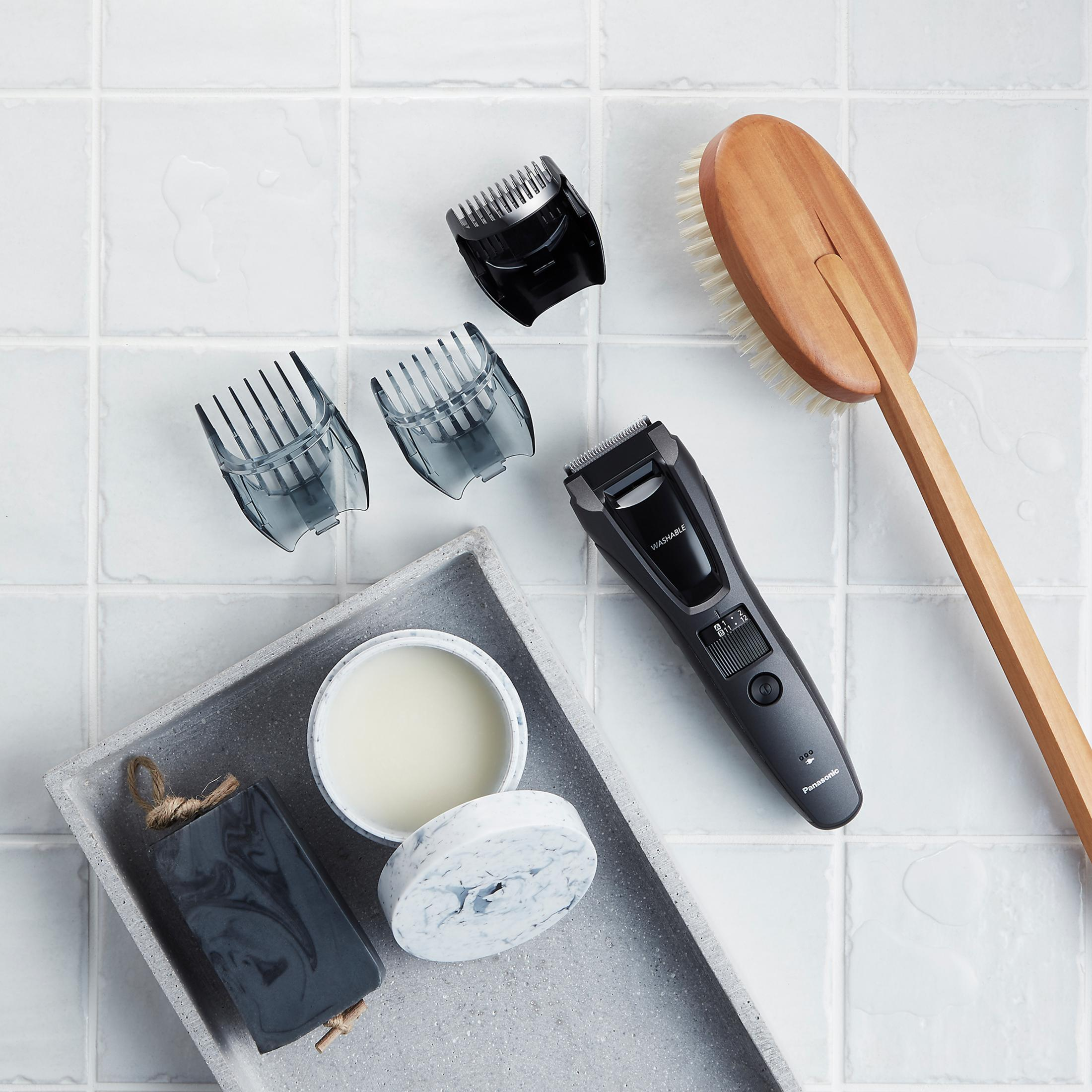 Czarna maszynka do brody z nasadkami na białej, kafelkowej powierzchni.