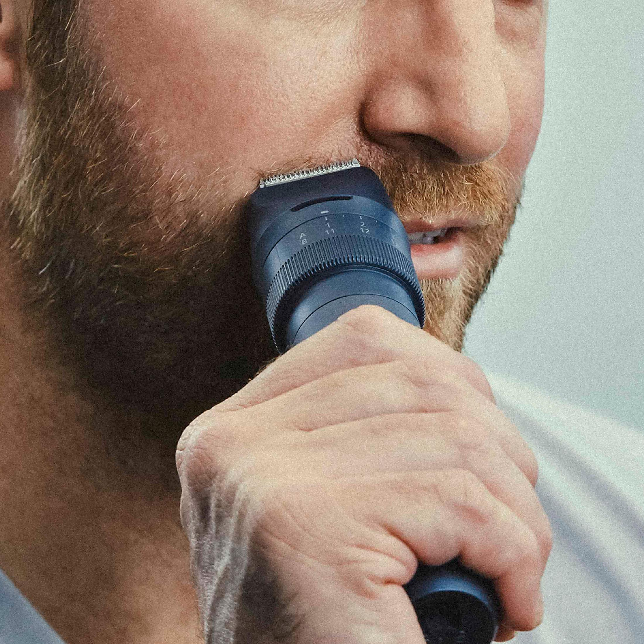 Mężczyzna przycina brodę trymerem, zbliżenie.