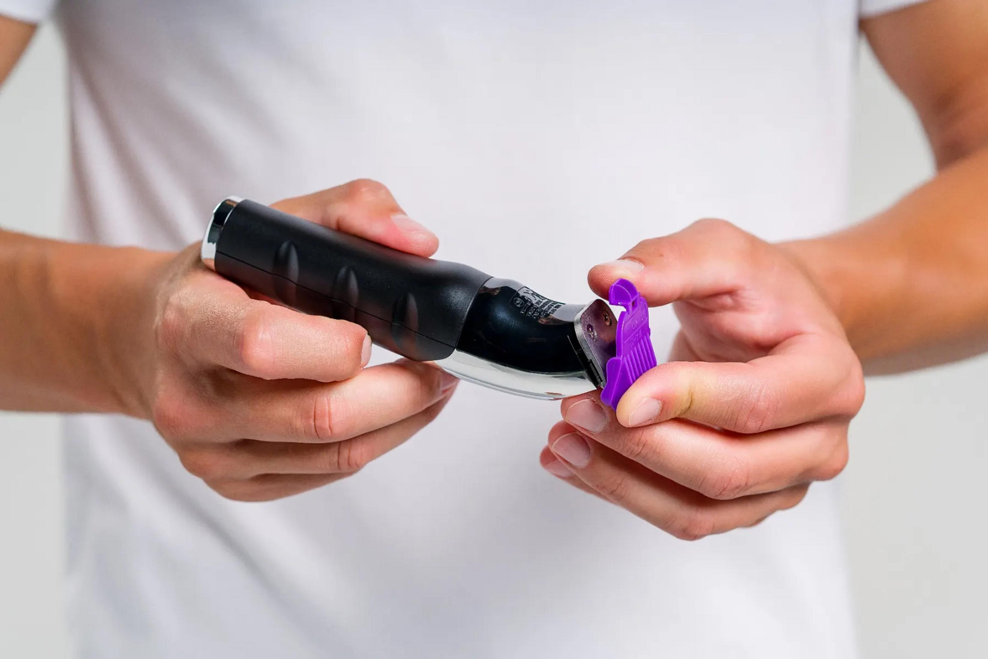 Osoba trzyma czarny trymer z fioletową nasadką.