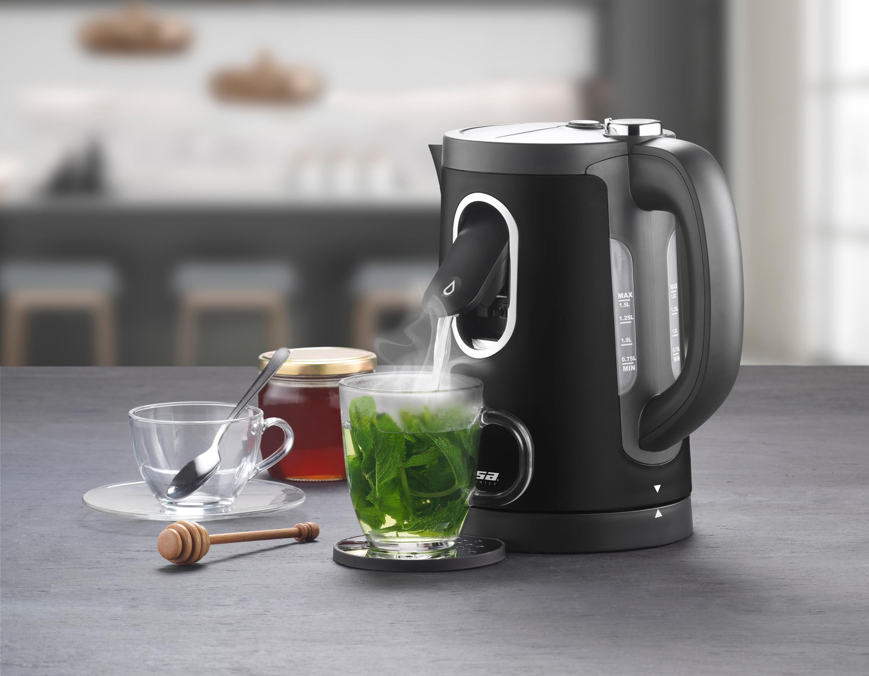 Ein schwarzer Wasserkocher gießt dampfendes Wasser in eine Tasse mit Minze. Daneben stehen Honig und eine leere Tasse.