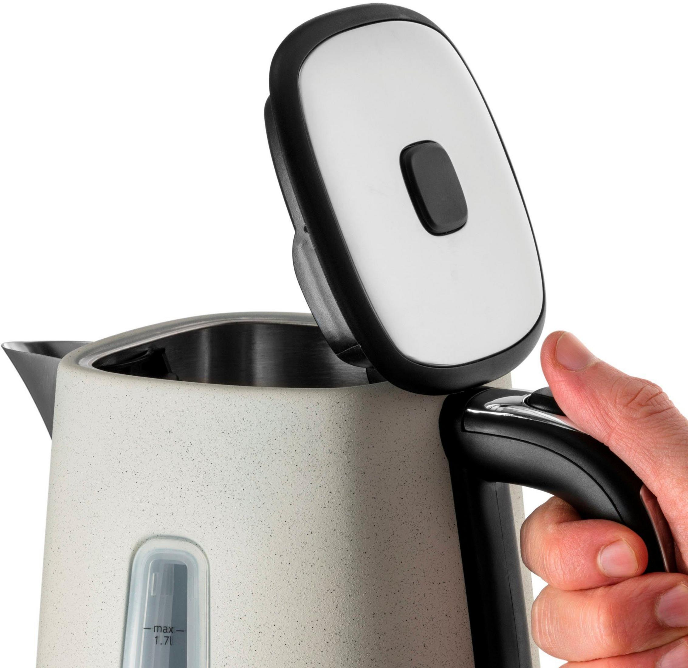 Dłoń otwiera pokrywkę kremowego czajnika z czarną rączką.