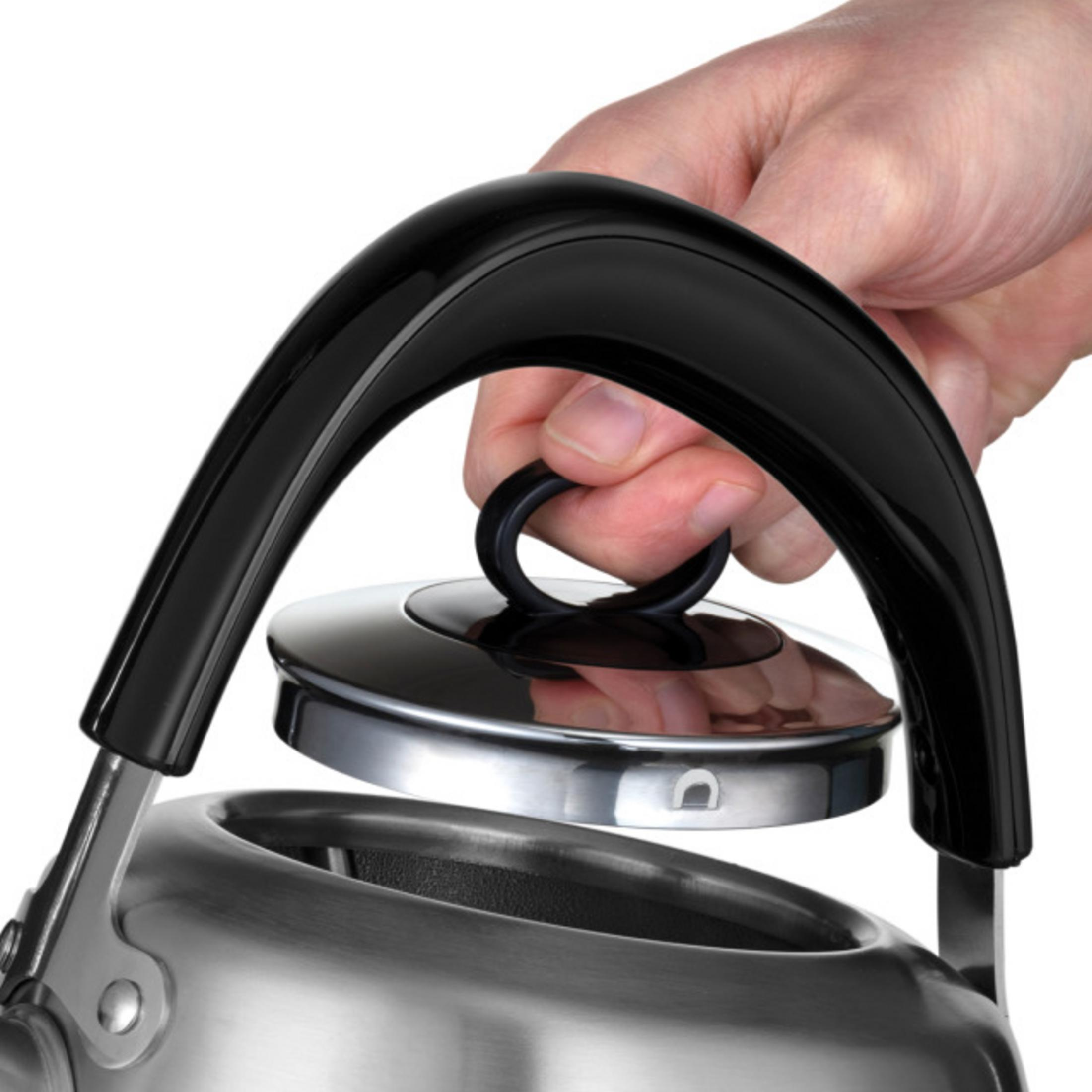 Dłoń otwiera pokrywkę czajnika z czarną rączką i metalem.