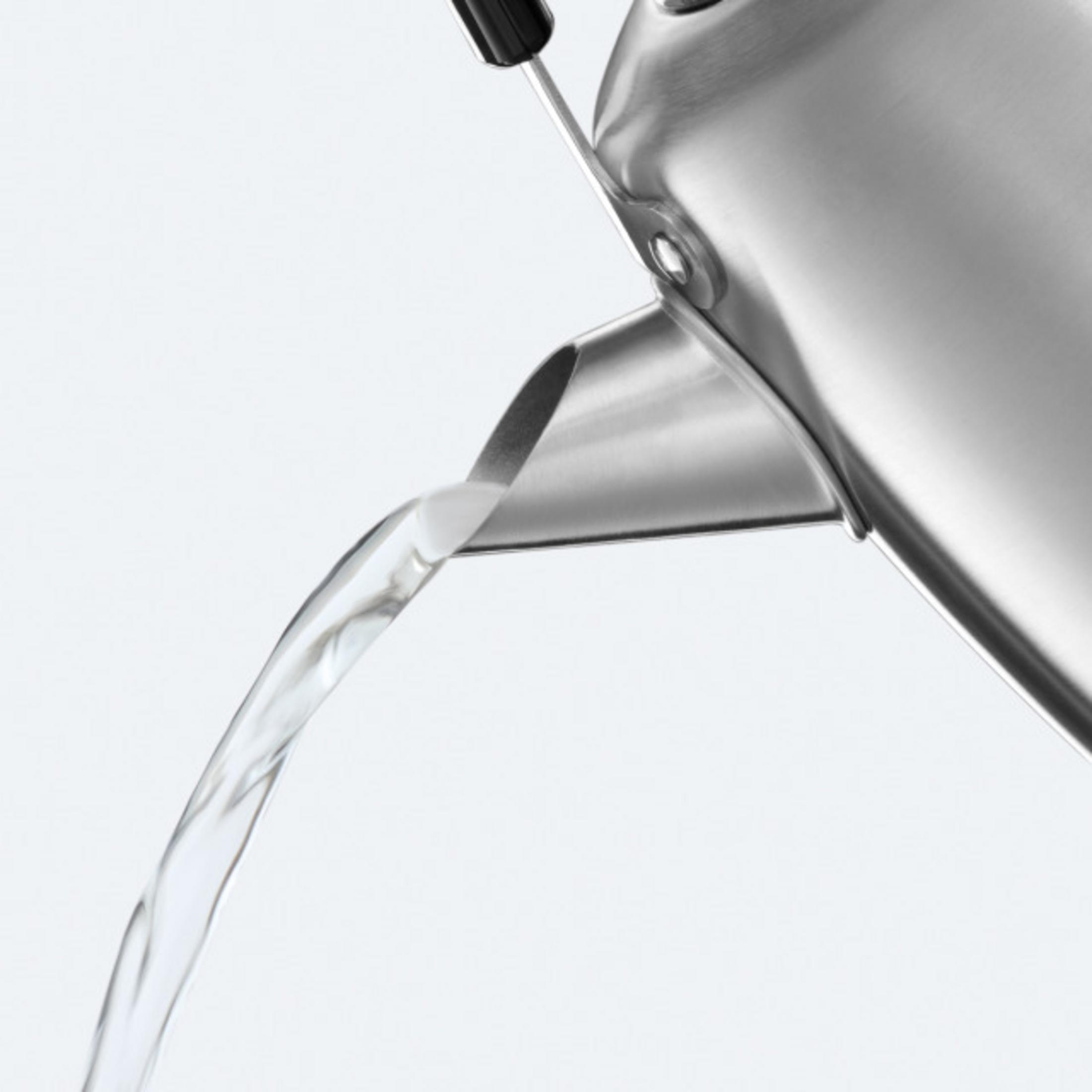 Woda płynie z metalowego dzbanka z czarnym uchwytem.