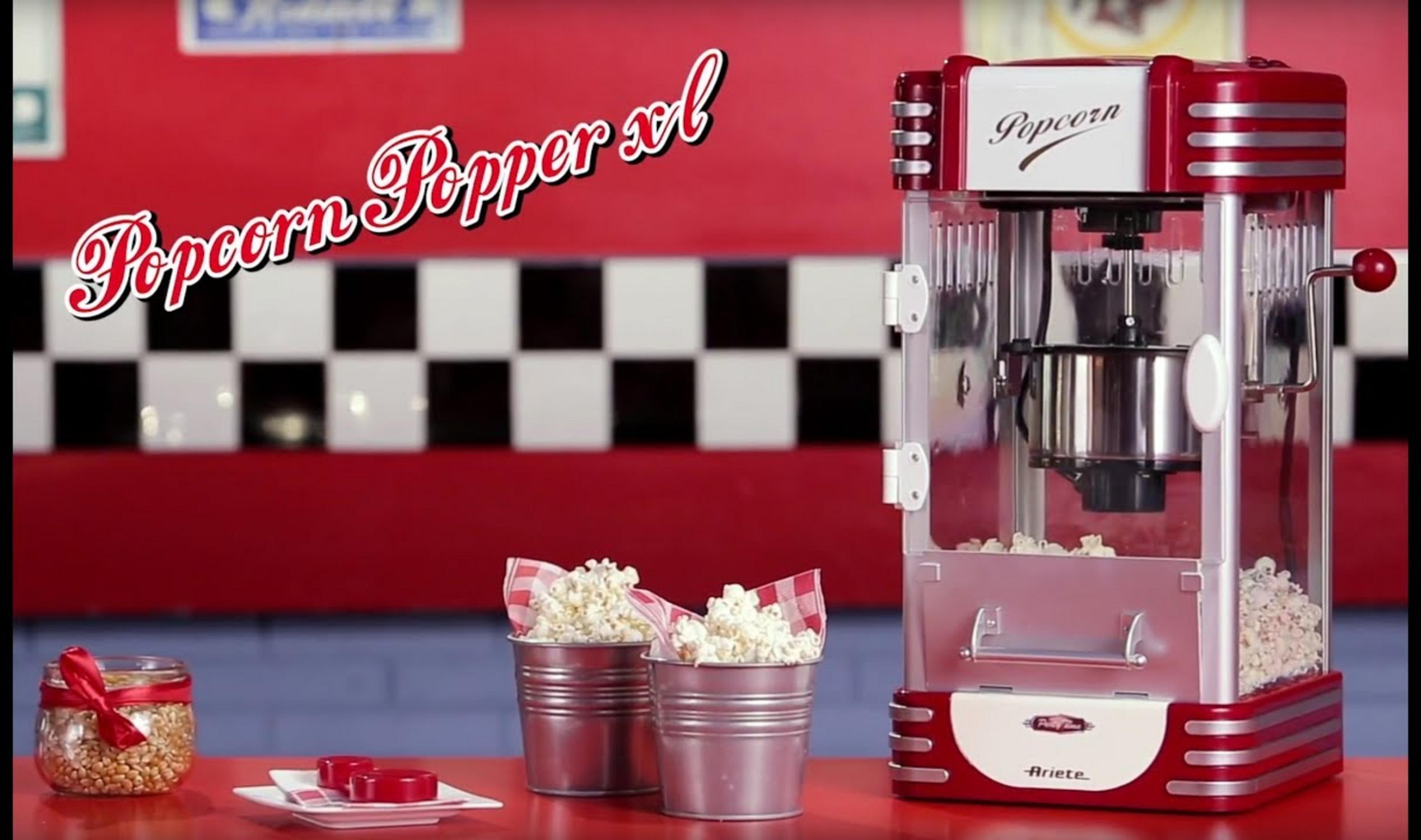 Una macchina per popcorn rossa retrò con popcorn in secchi e un barattolo di mais.