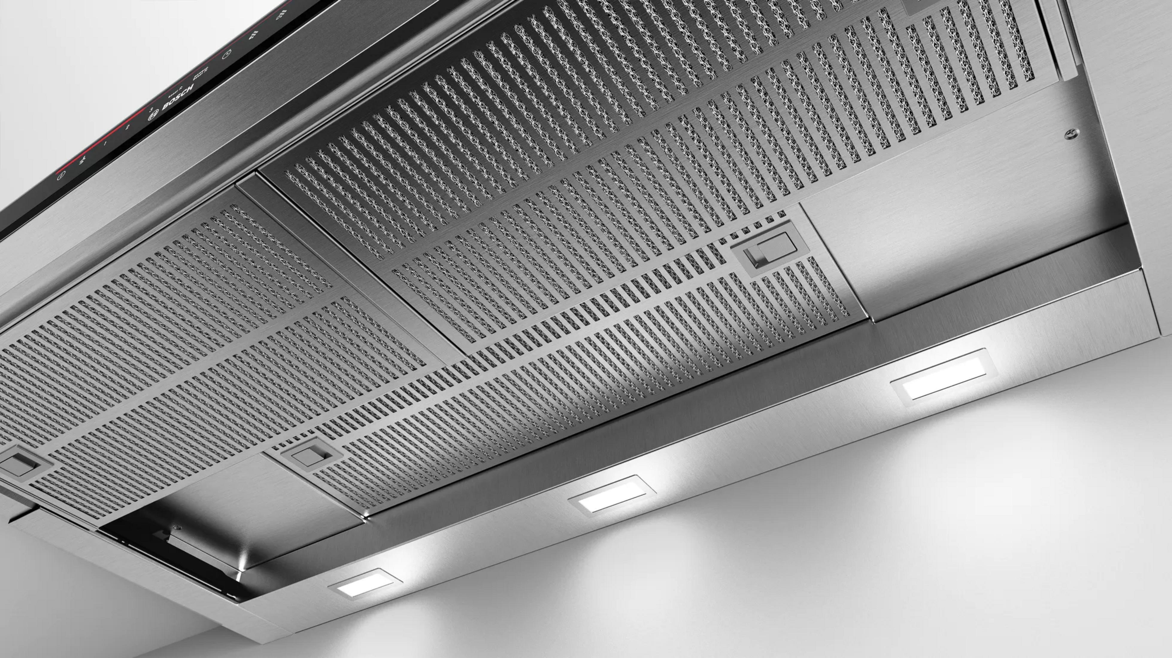 Campana extractora de acero inoxidable con superficie perforada y luces integradas.