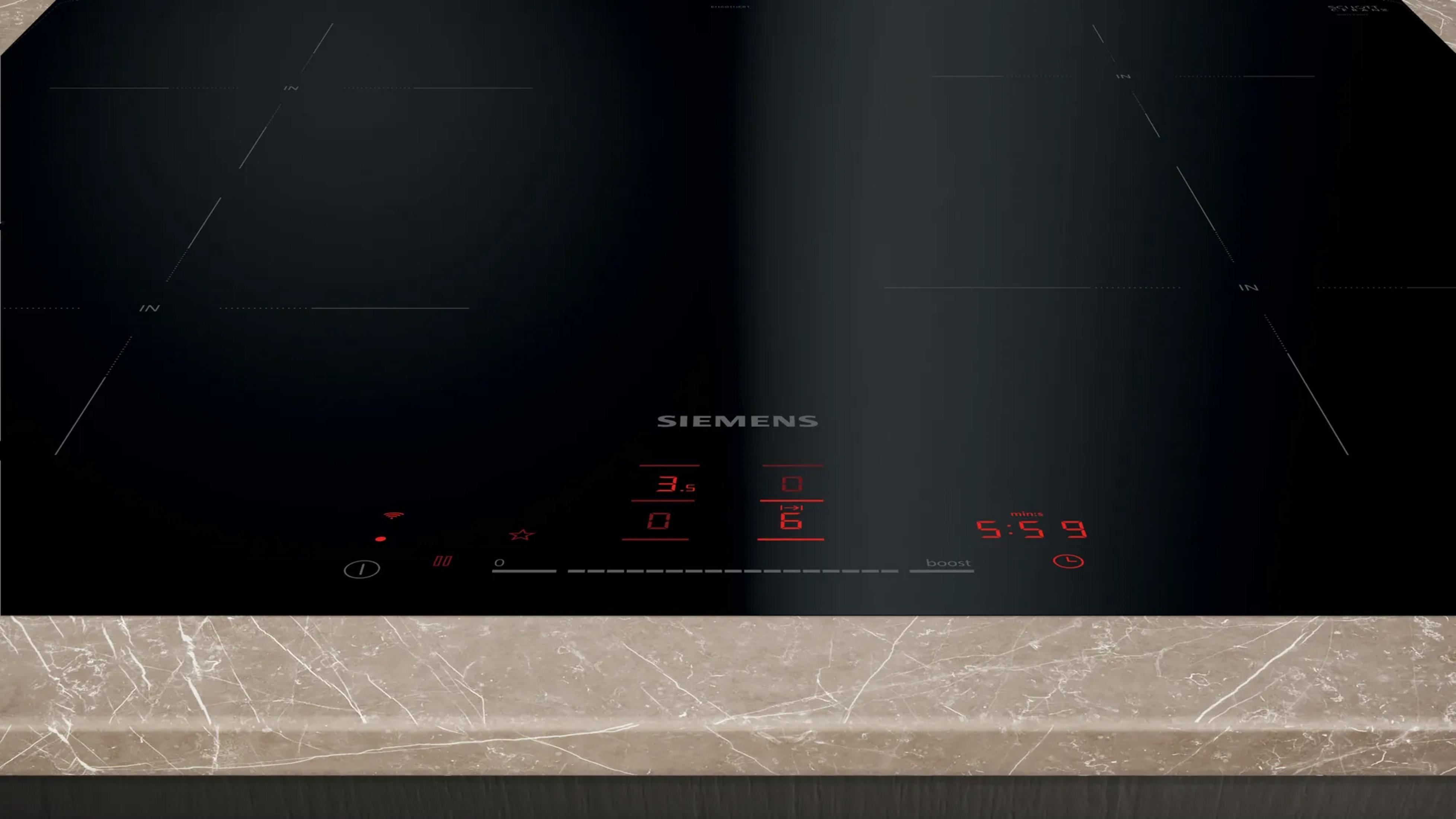 Une plaque à induction Siemens noire avec écrans numériques rouges, minuterie et commandes.