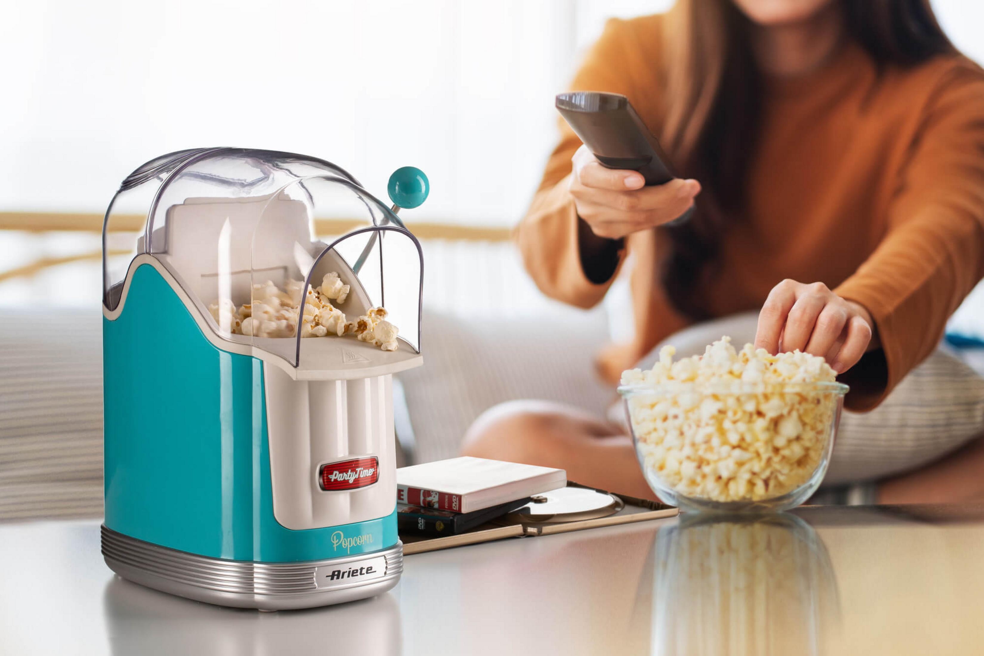 Macchina per popcorn turchese con popcorn freschi accanto a una ciotola.
