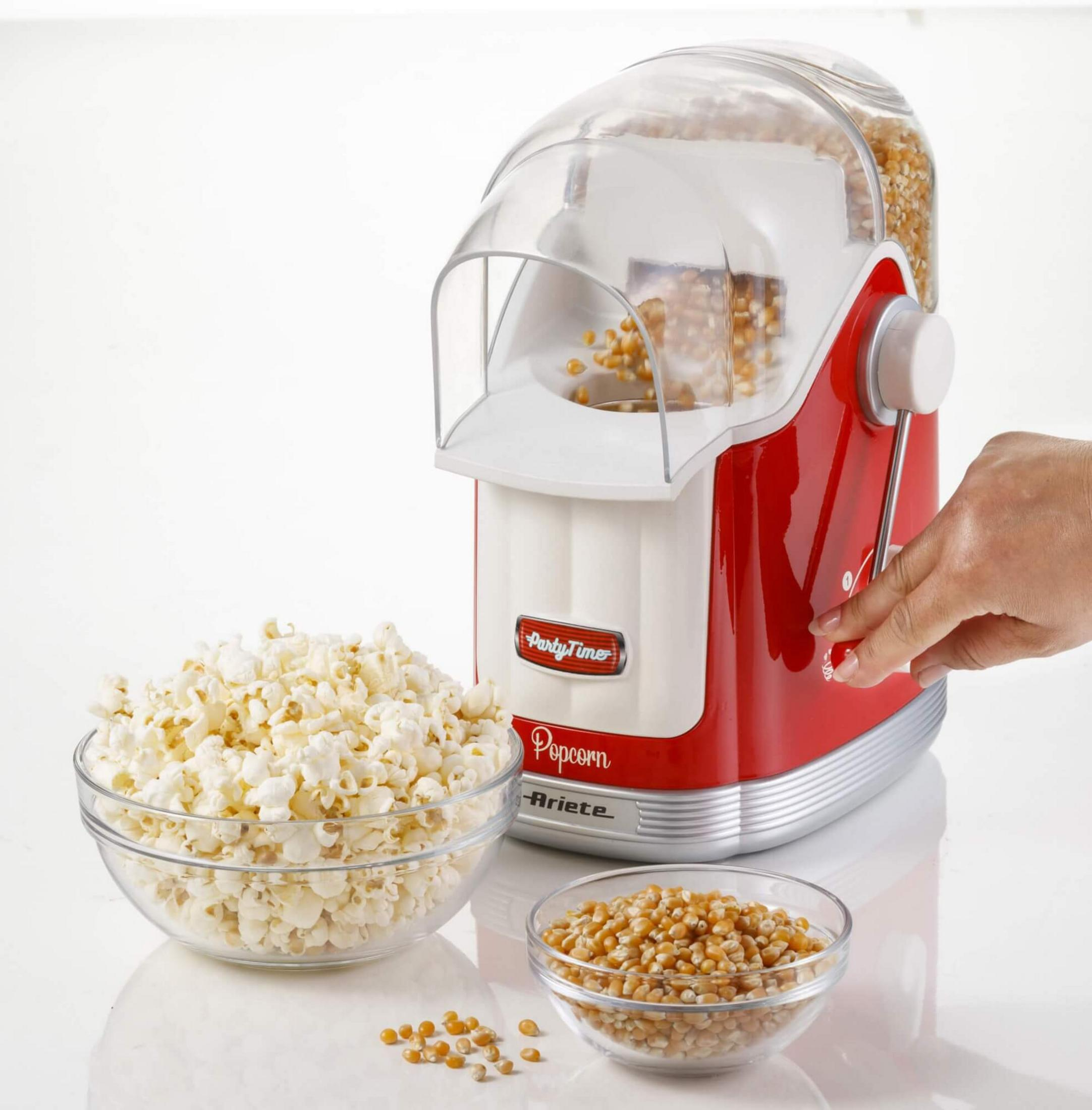 Een rood-witte popcornmachine met een kom popcorn en maïskorrels.
