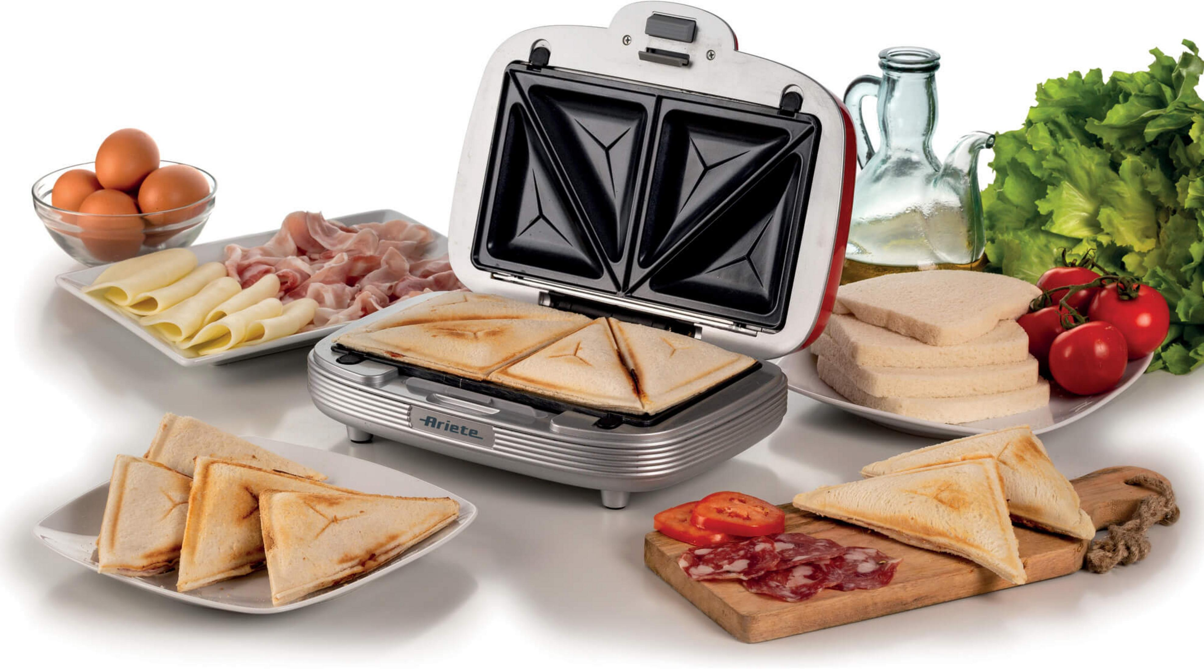A sandwich maker with finished sandwiches, eggs, cheese, ham, and vegetables.