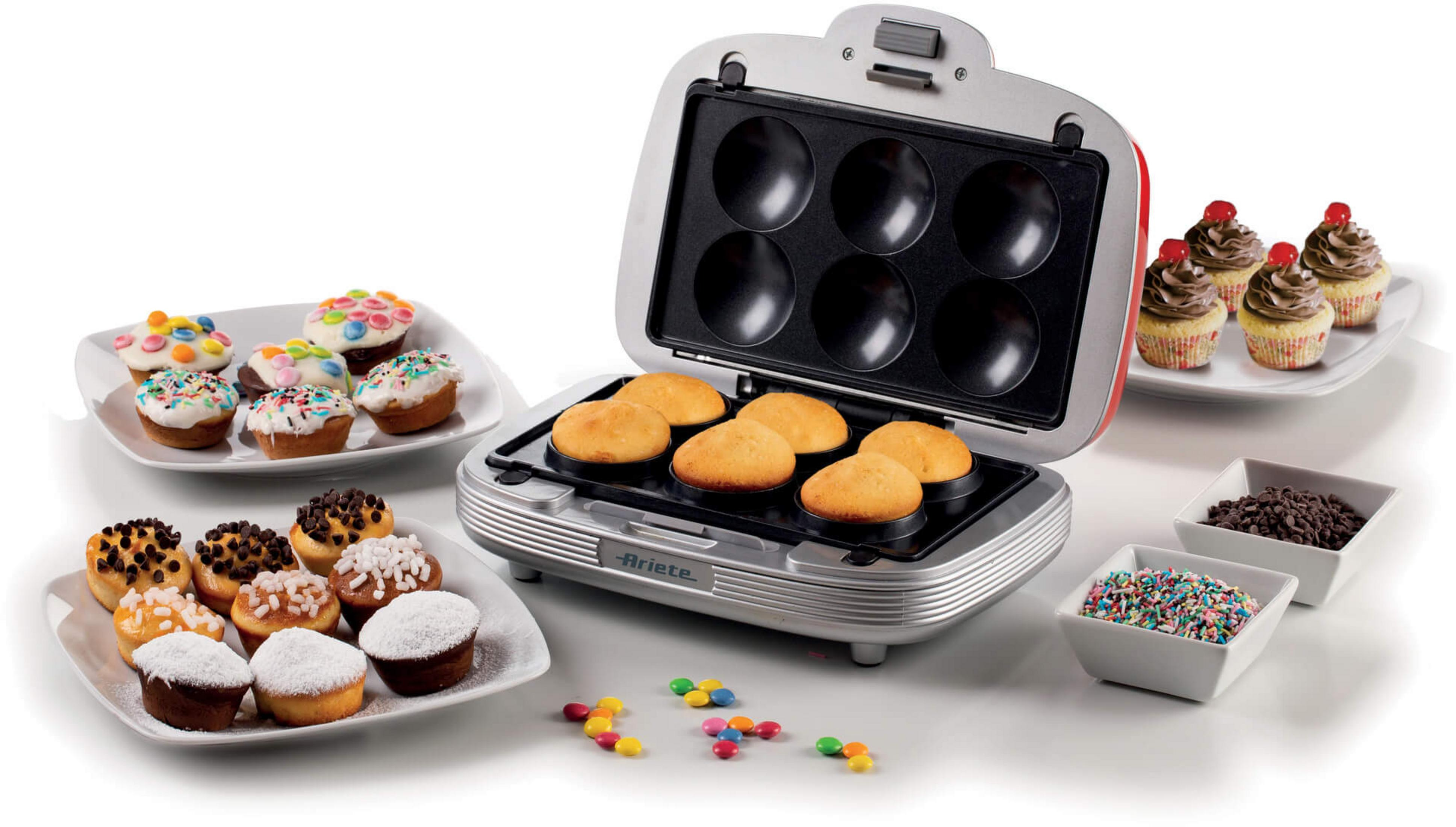 An open cupcake maker with baked batter, decorated cupcakes, and sprinkles.